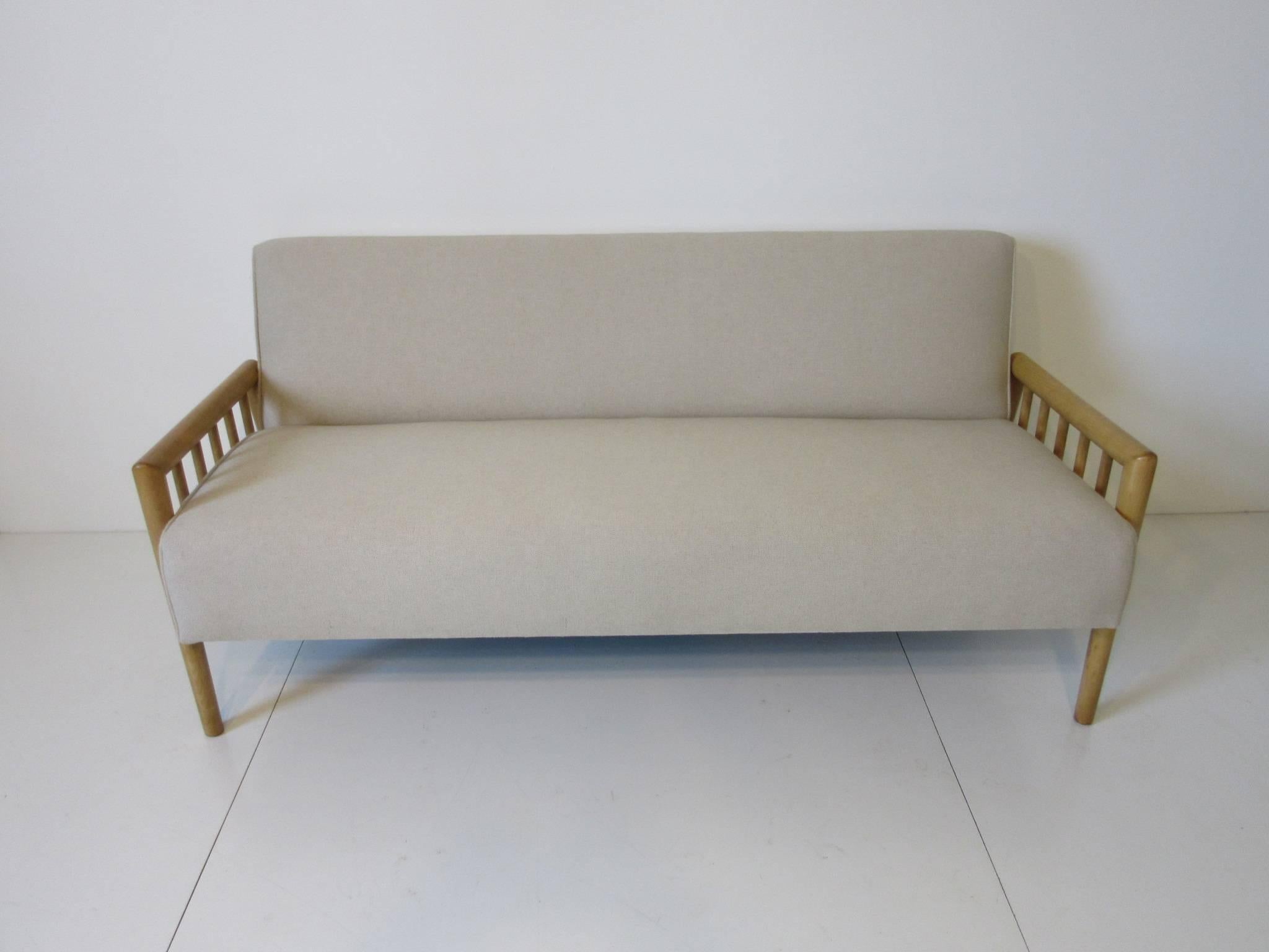 A linen upholstered smaller sized Gibbings loveseat sofa with open end arms and frame, a simple but elegant design from the well respected designer. Manufactured by the Widdicomb Furniture Company.