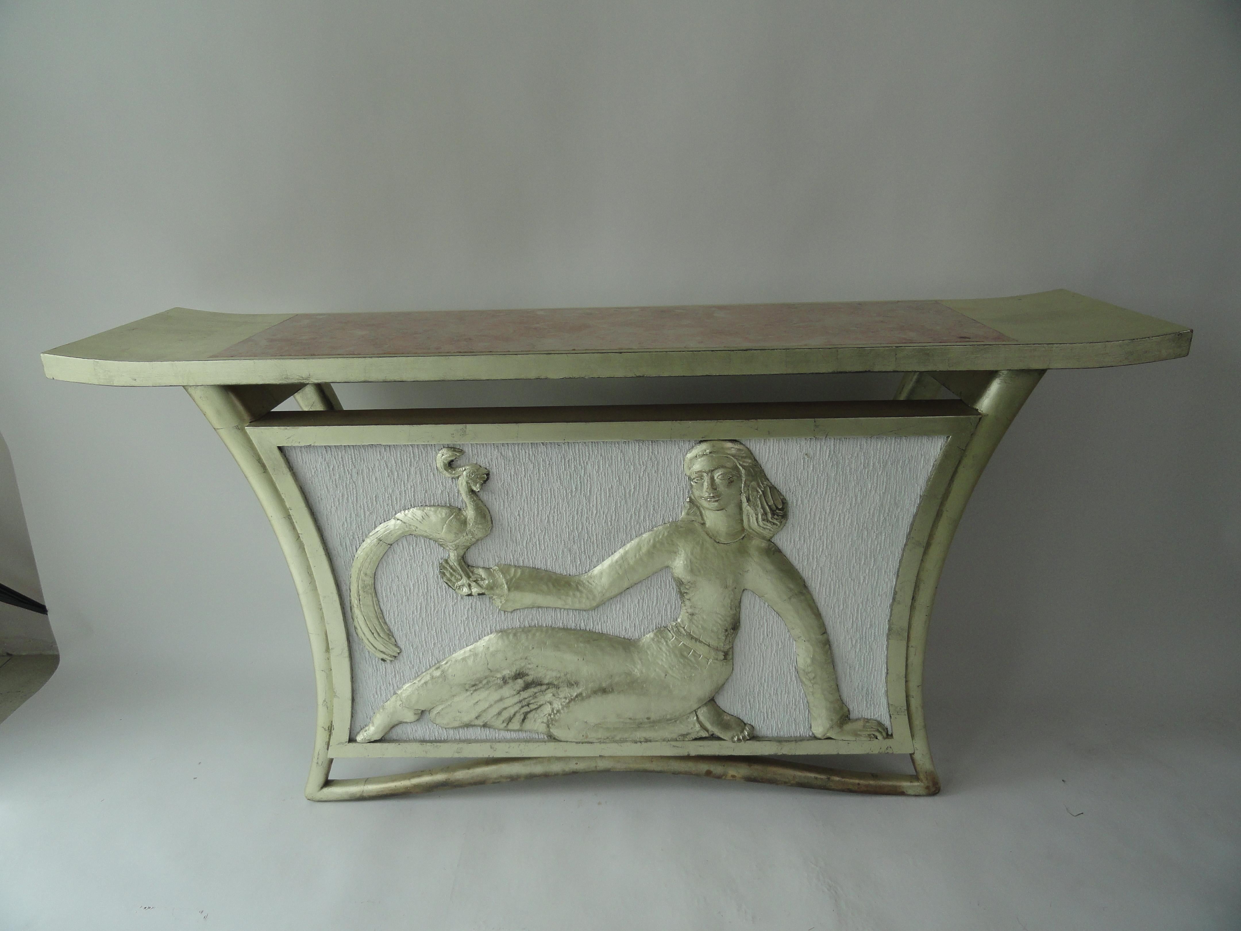 Custom T.H. Robsjohn-Gibbings table with marble insert on top. Carved female figure, Lydia, with peacock. Newer silver leaf finish on frame. White painted fabric background.
Table came from a Palm Beach estate.