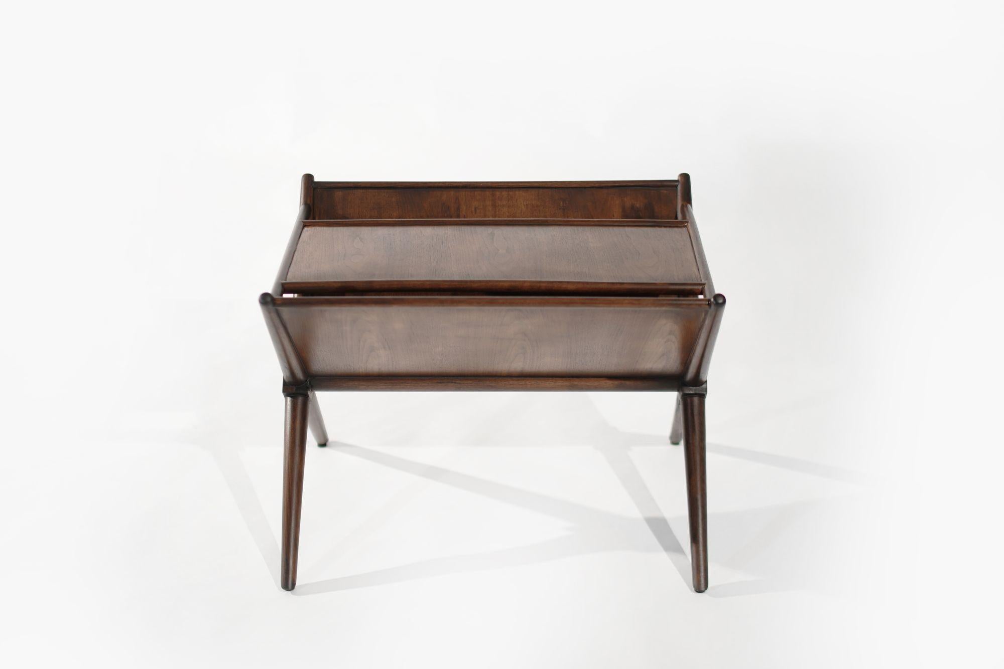 This exquisite walnut magazine table, designed by the renowned T.H. Robsjohn-Gibbings, dates back to the mid-20th century, circa 1950-1959. Its distinctive x-shaped framework exemplifies Robsjohn-Gibbings' elegant and functional design philosophy.