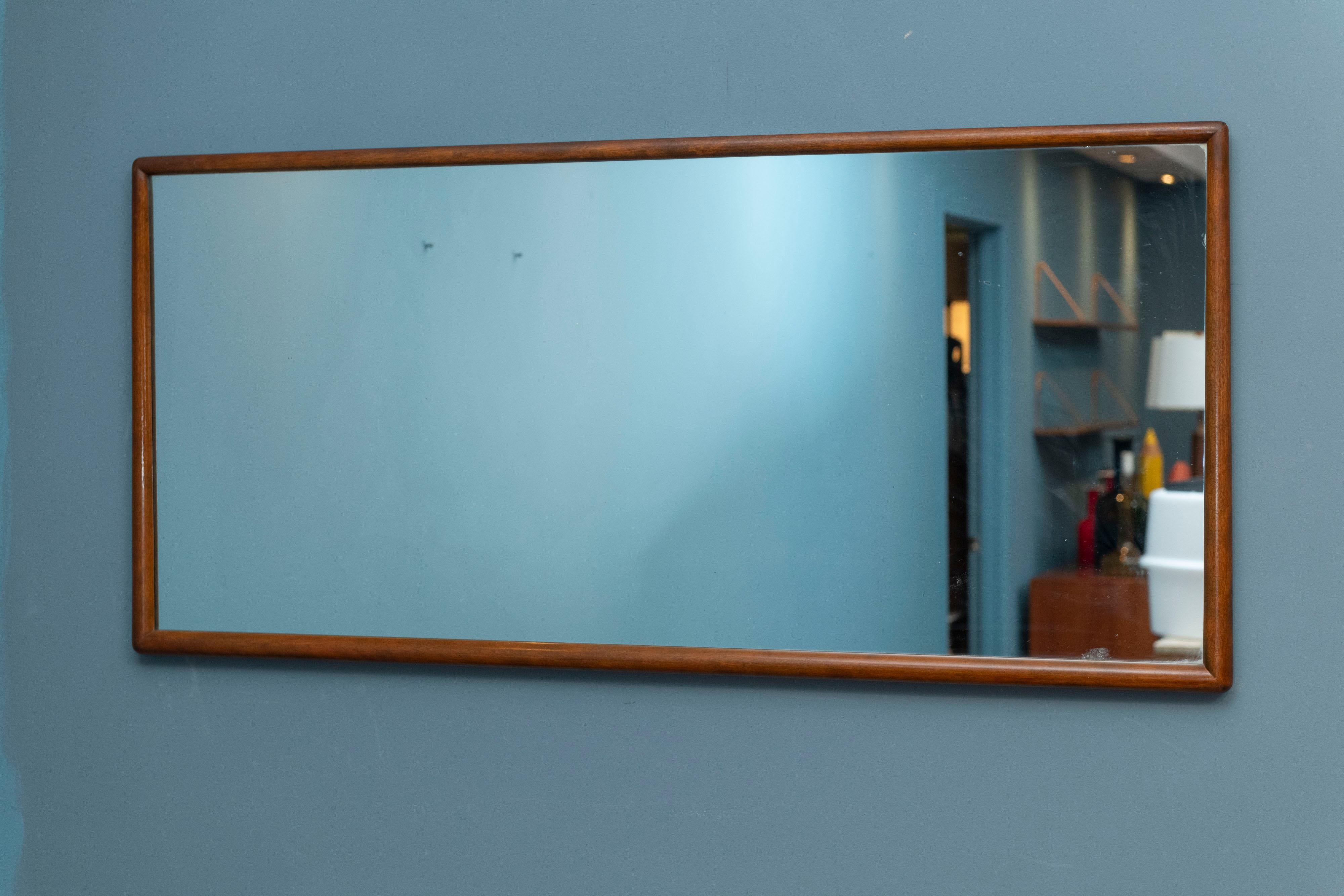 T.H. Robsjohn-Gibbings wall mirror for Widdicomb Furniture company. Sculpted walnut frame with rounded edges and corners throughout
 that start thinner at the top and widen towards the bottom. 