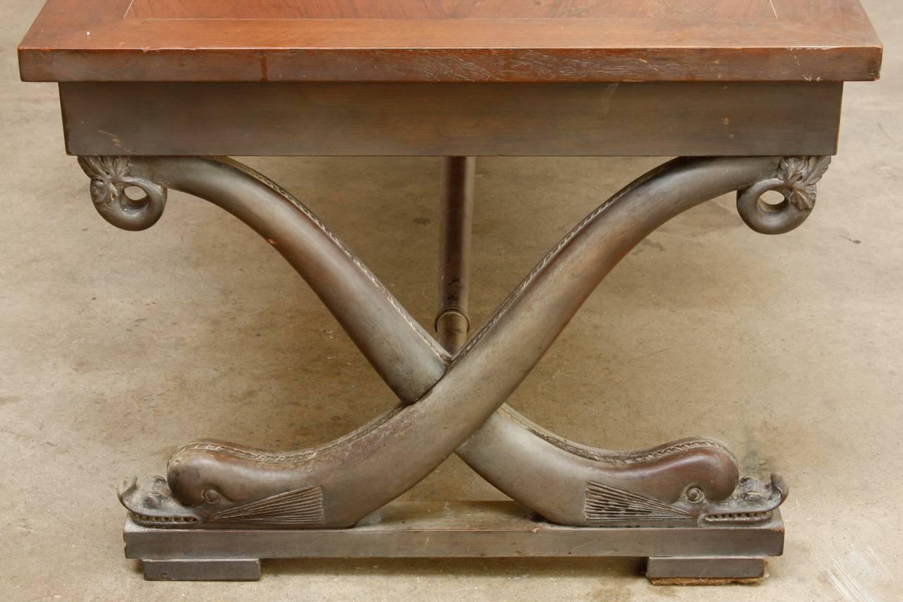 Rare T.H. Robsjohn-Gibbings (1905-1976) cocktail table for Baker furniture made in the neoclassical taste. Features an X-form curule style supports with dolphin motifs conjoined by a long stretcher. The top has a beautifully veneered four panel