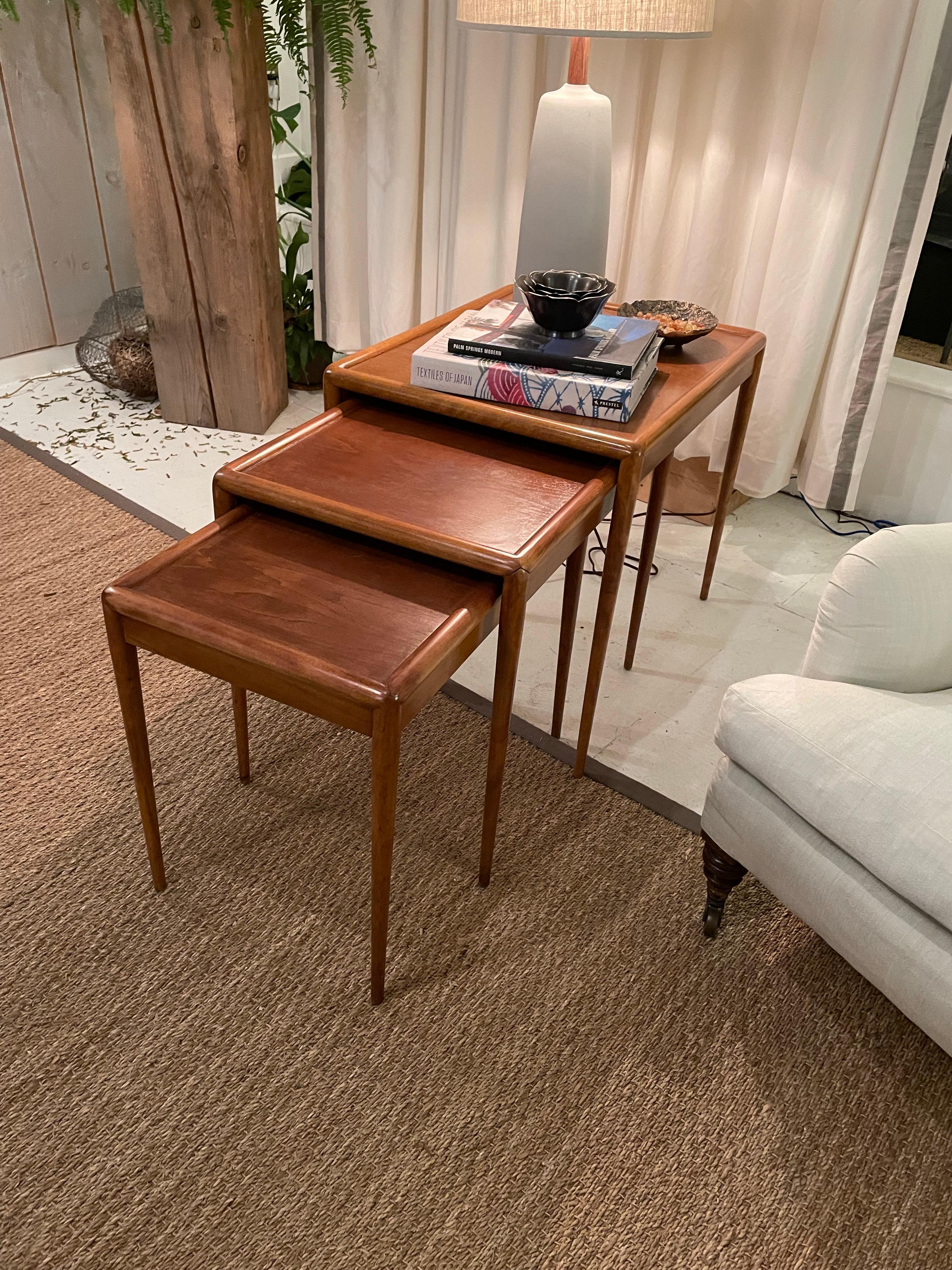 T. H. Robsjohn-Gibbings designed this set of three richly grained mahogany nesting tables for Widdicomb. Splayed mitered edge construction of legs are seamlessly connected to the frame of the table. Made from rich mahogany with natural varied tones.