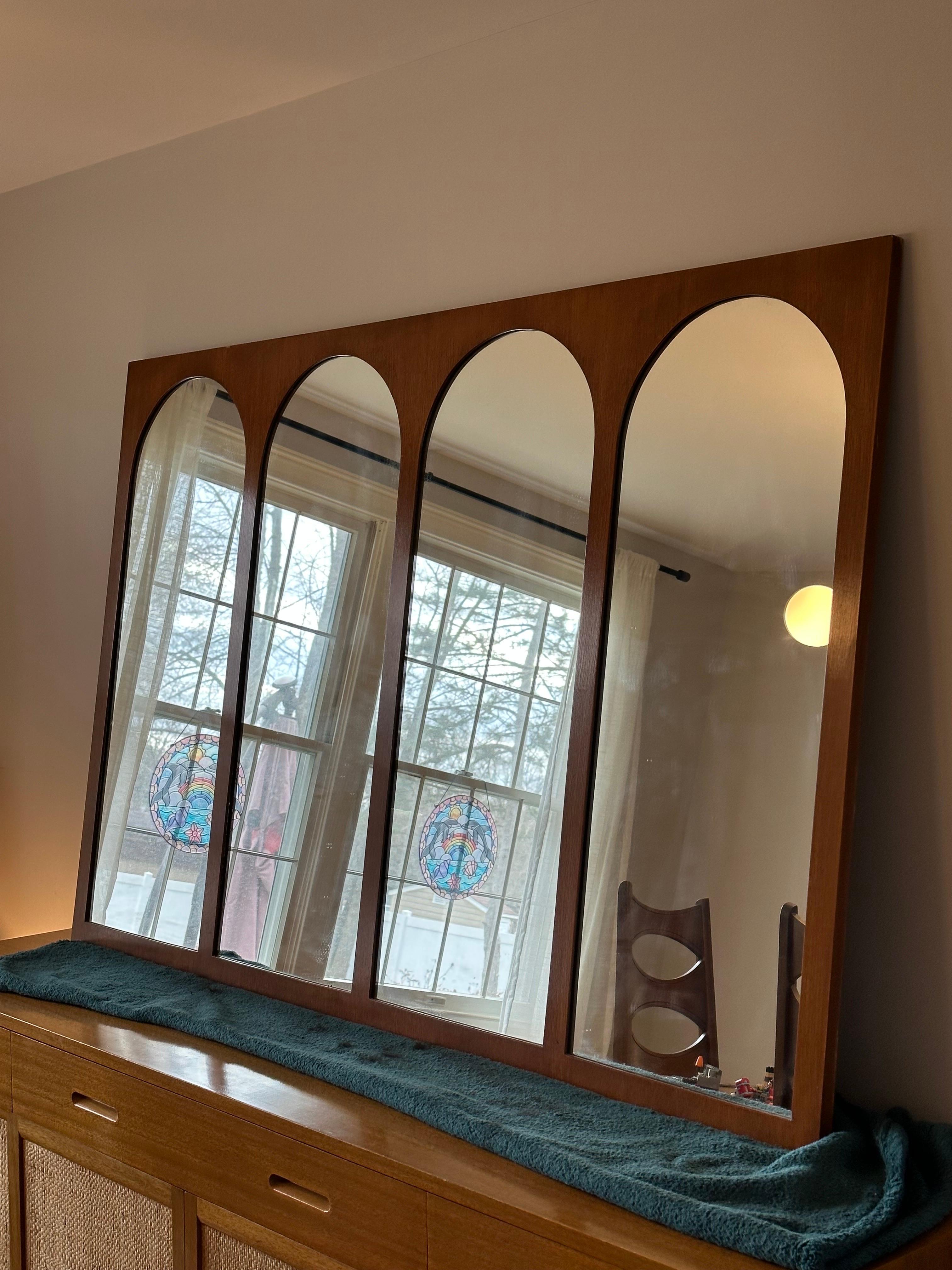 A monumental wall mirror designed by T.H. Robsjohn-Gibbings for Widdicomb. Features four arched mirror sections framed in walnut. A unique and versatile piece that is every bit functional as it is art. This line of furniture from Robsjohn-Gibbings
