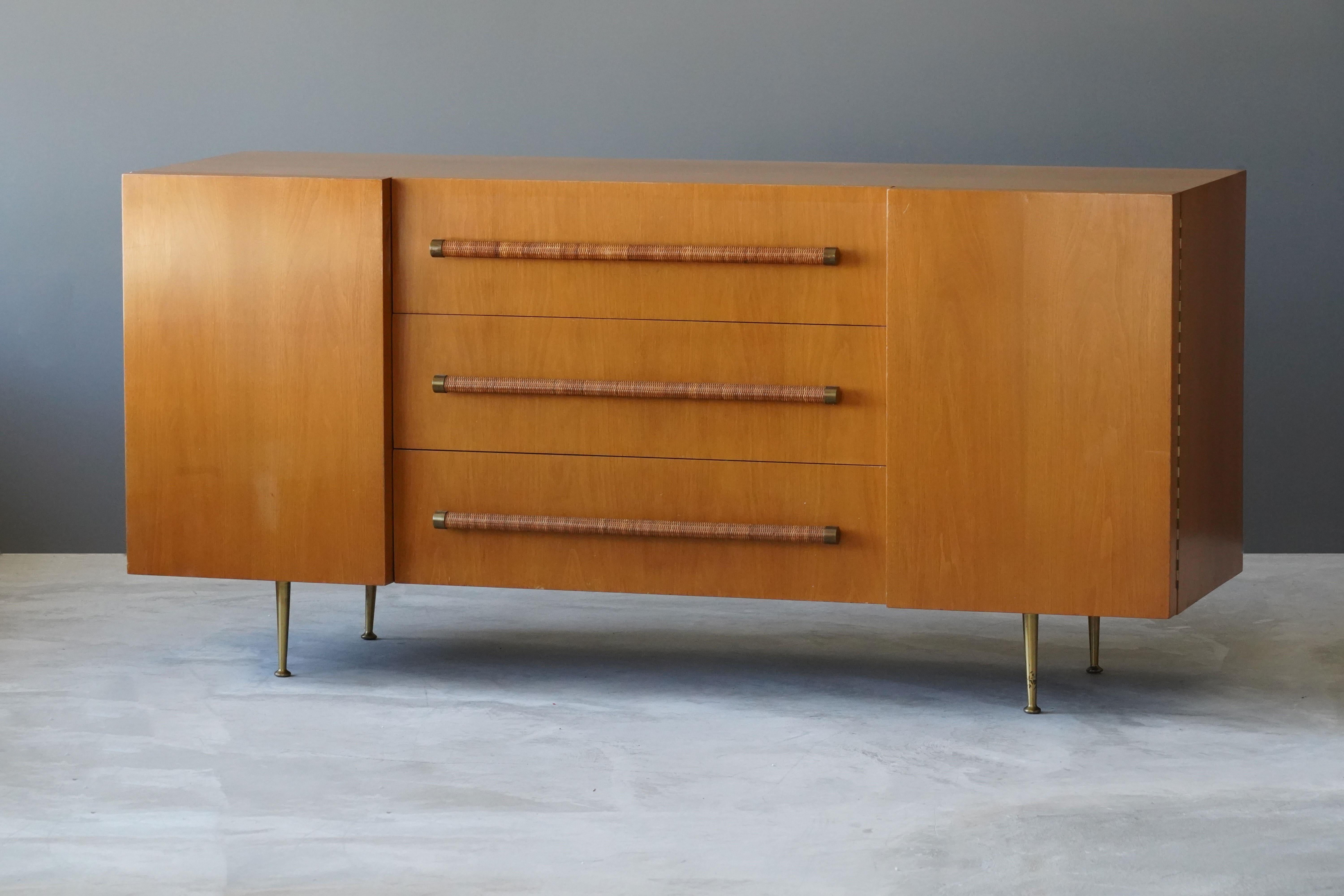 An elegant and practical cabinet/sideboard/credenza with brass/rattan grips and brass legs. From the celebrated series of furniture T.H. Robsjohn-Gibbings designed for Widdicomb Furniture Company. 

Other designers of the period include Paul Frankl,