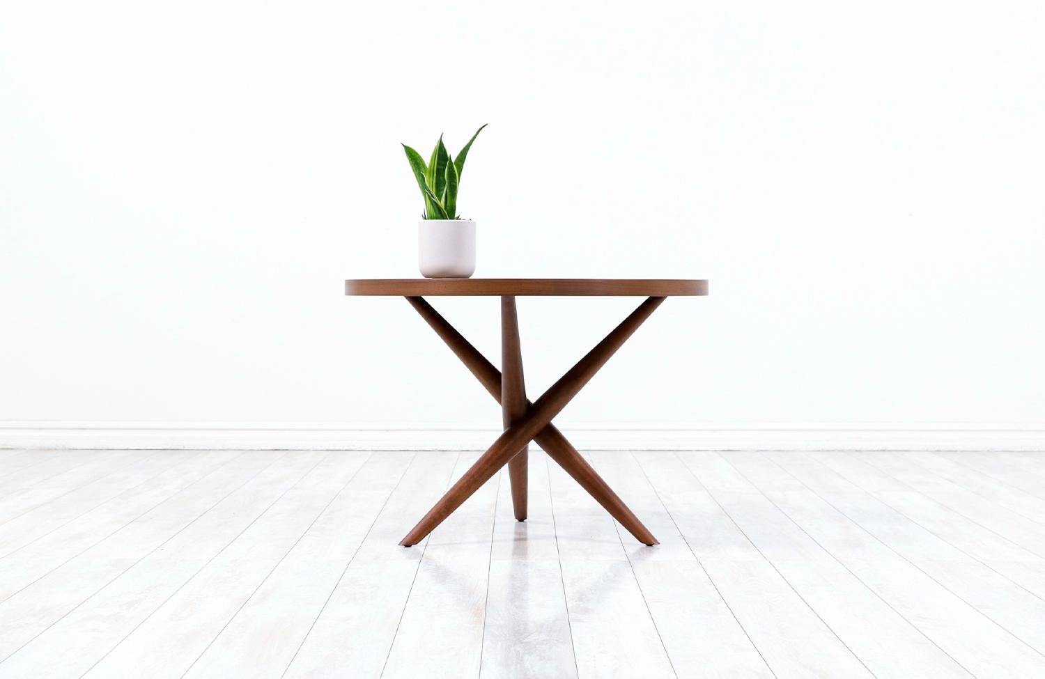 Elegant modern side table designed by T.H. Robsjohn-Gibbings for Widdicomb in the United States circa 1950s. This sophisticated side table features a softly contoured walnut wood top over a tripod base creating a handsome silhouette with three