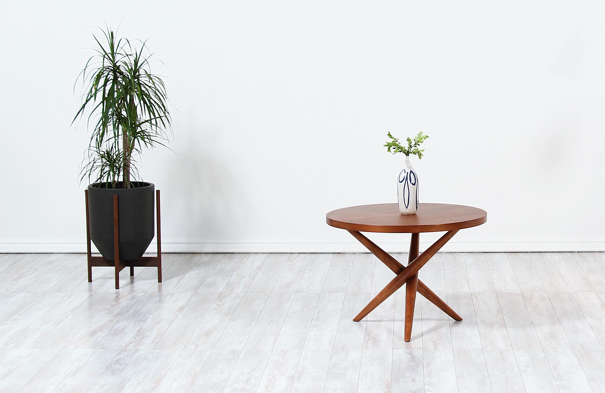 Elegant modern side table designed by T.H. Robsjohn-Gibbings for Widdicomb in the United States circa 1950s. This sophisticated side table features a softly contoured walnut wood top over a tripod base creating a handsome silhouette with three