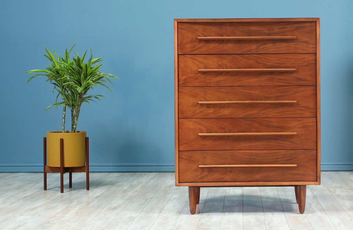 Chest of drawers designed by T.H. Robsjohn-Gibbings and manufactured by Widdicomb in the United States circa 1950’s. This design features a tall walnut wood body that sits on four tapered legs. The front, including the drawers, is concaved giving