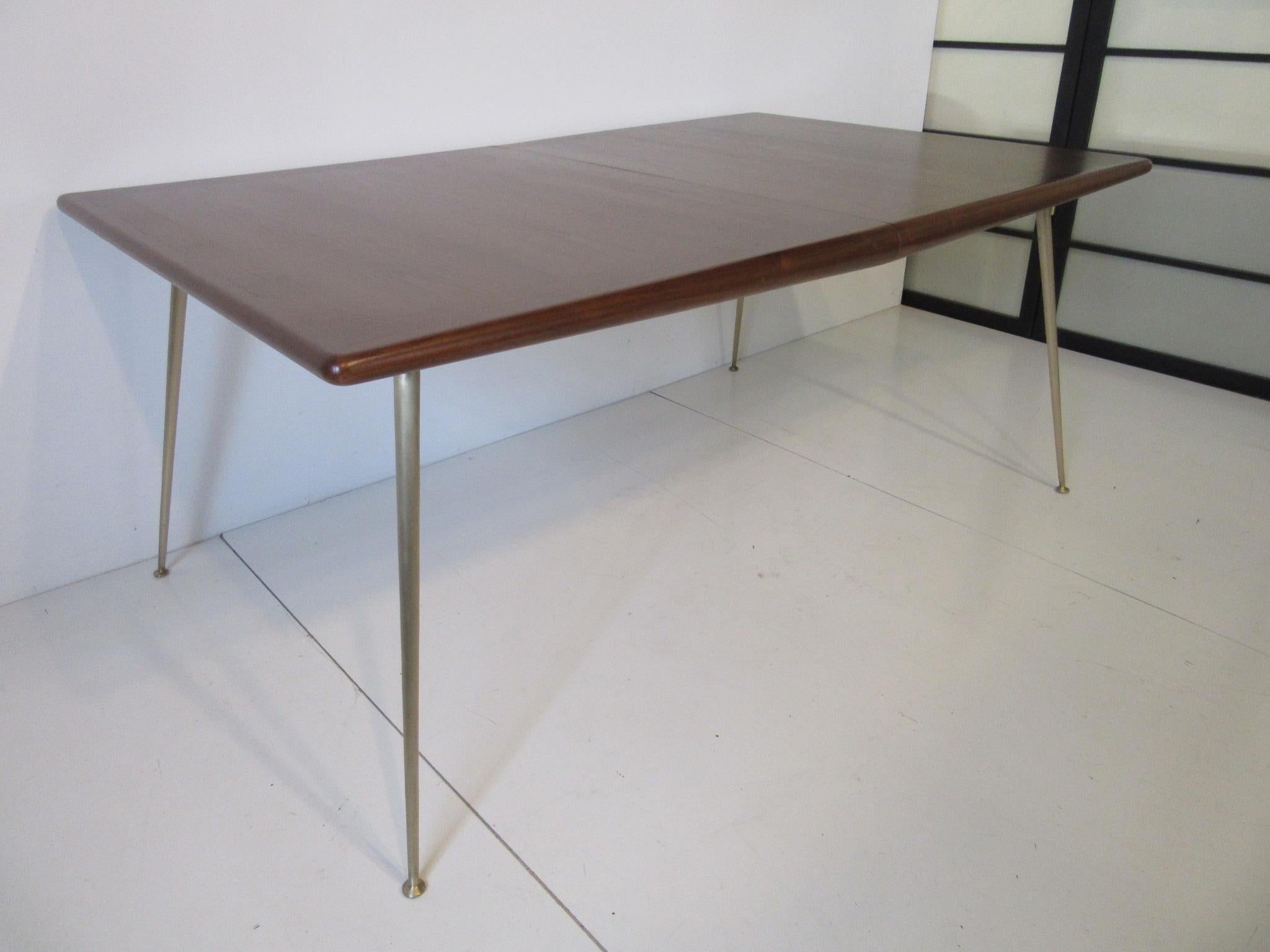 A well crafted walnut dining table with bull nose edge sitting on solid polished satin brass legs, a hard to find piece because of its cost in the 1950s and only found in the fineness of homes . This table was purchased from the original owners and