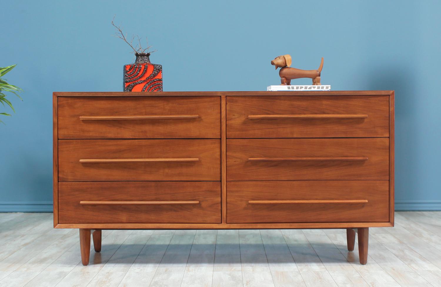 Dresser designed by T.H. Robsjohn-Gibbings and manufactured by Widdicomb in the United States circa 1950’s. This design features a walnut wood body that sits on four tapered legs. The front, including the drawers, is concaved giving this dresser a