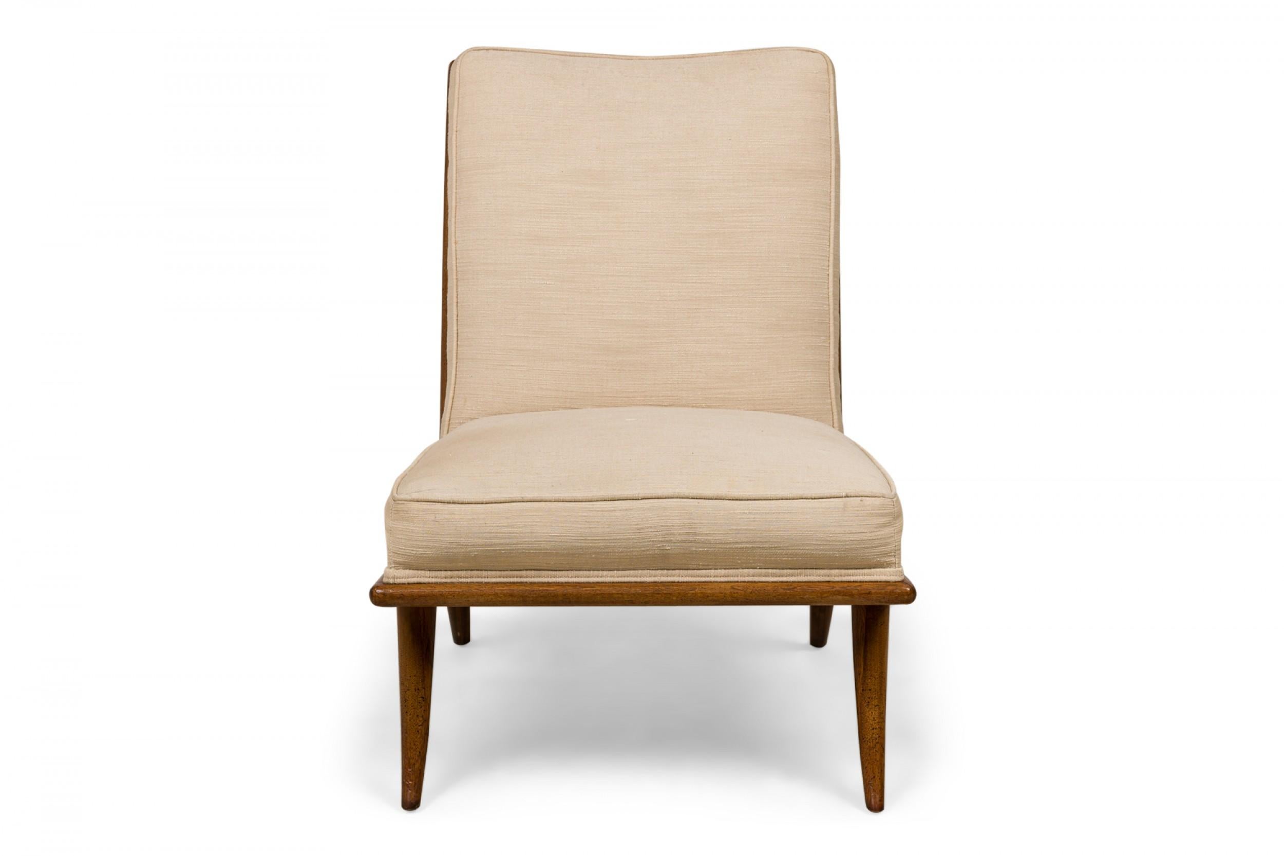 Mid-Century slipper / side chair with beige fabric upholstery and a walnut frame resting on four gently curved and tapered legs. (T.H. ROBSJOHN-GIBBINGS FOR WIDDICOMB)(Similar pieces: DUF0545, DUF0546)
