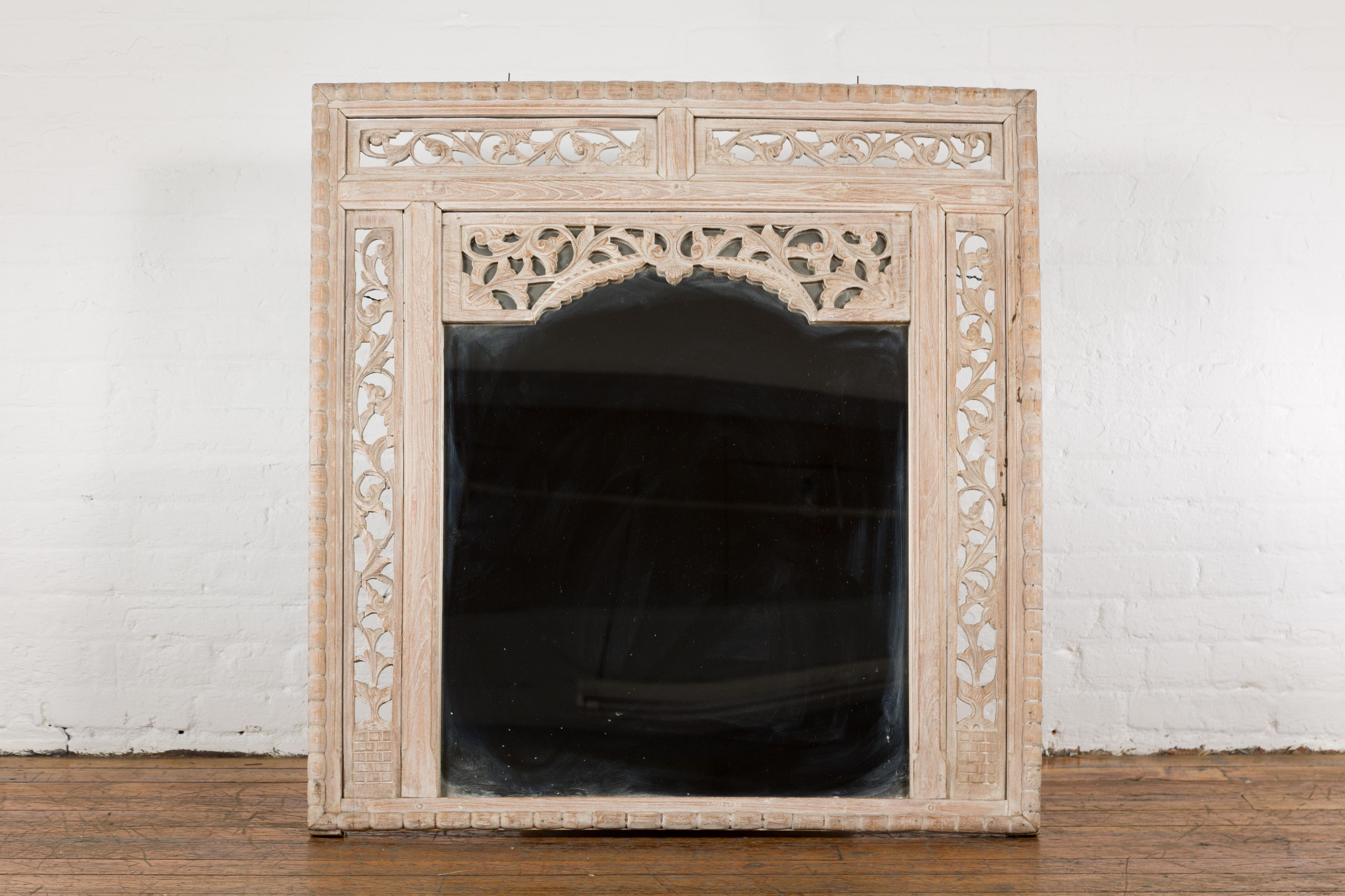 An antique painted Thai mirror from the 19th century, with hand-carved scrolling floral décor. Exuding an air of grace and opulence, this painted Thai mirror from the 19th century beckons us with its hand-carved scrolling floral décor and serene