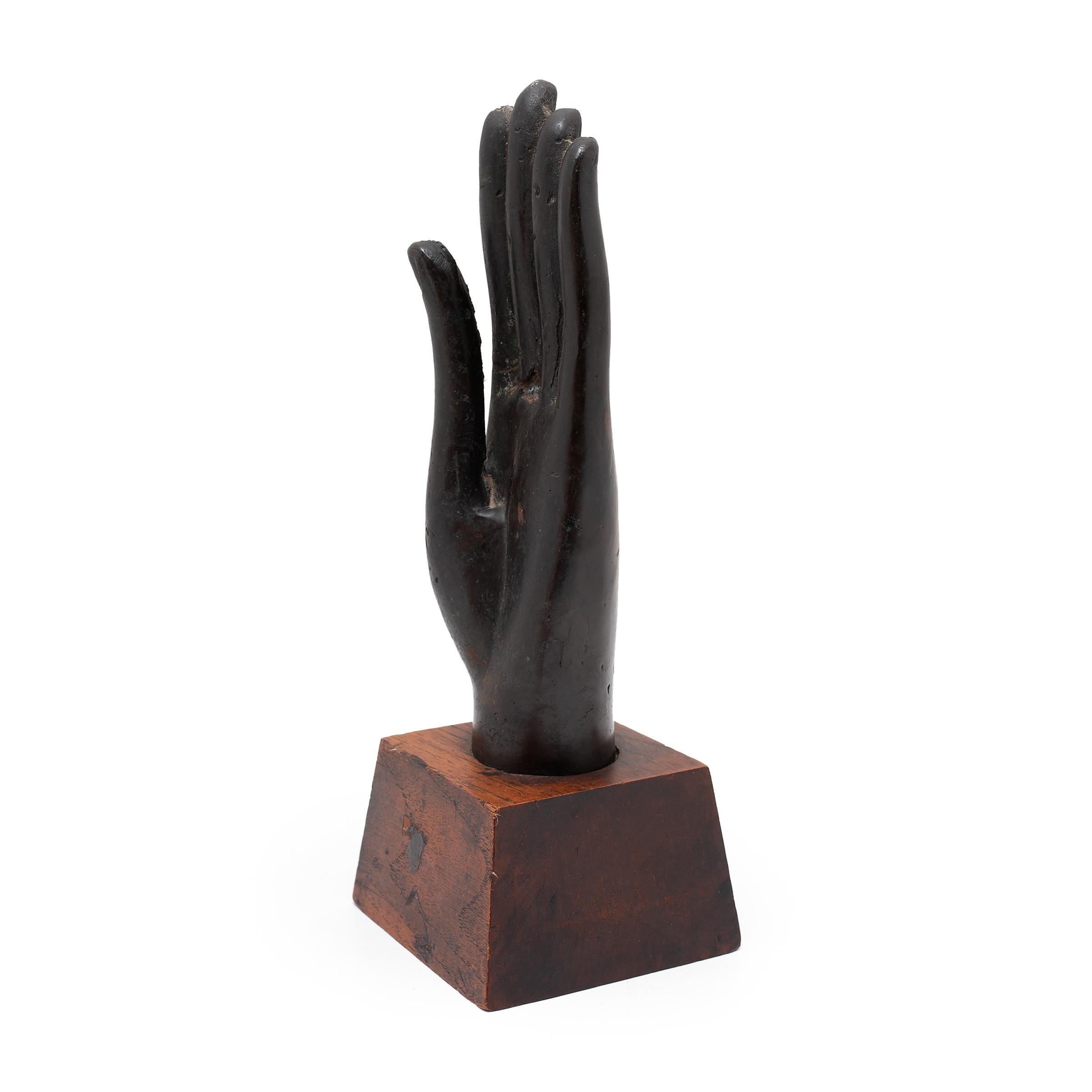 Cette sculpture thaïlandaise de la main de Bouddha, datant du XIXe siècle, est finement coulée en bronze et présente des traits réalistes ainsi qu'une belle patine sombre. La main est tenue vers le haut en Abhaya mudra, le geste de protection et de