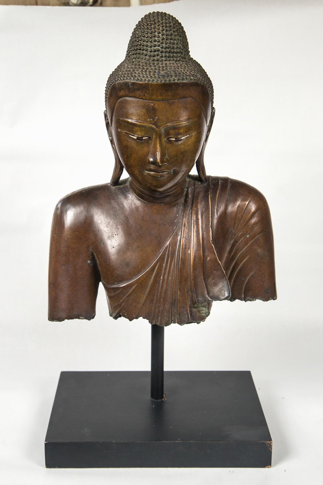 Fragment piece of the shoulders and head of this Buddha. Enameled eyes. Raised above a black base on a rod.
The overall dimensions in inches, are 23 tall, 11.75 wide and 14.5 deep
dimensions for the fragment itself are given below.
  