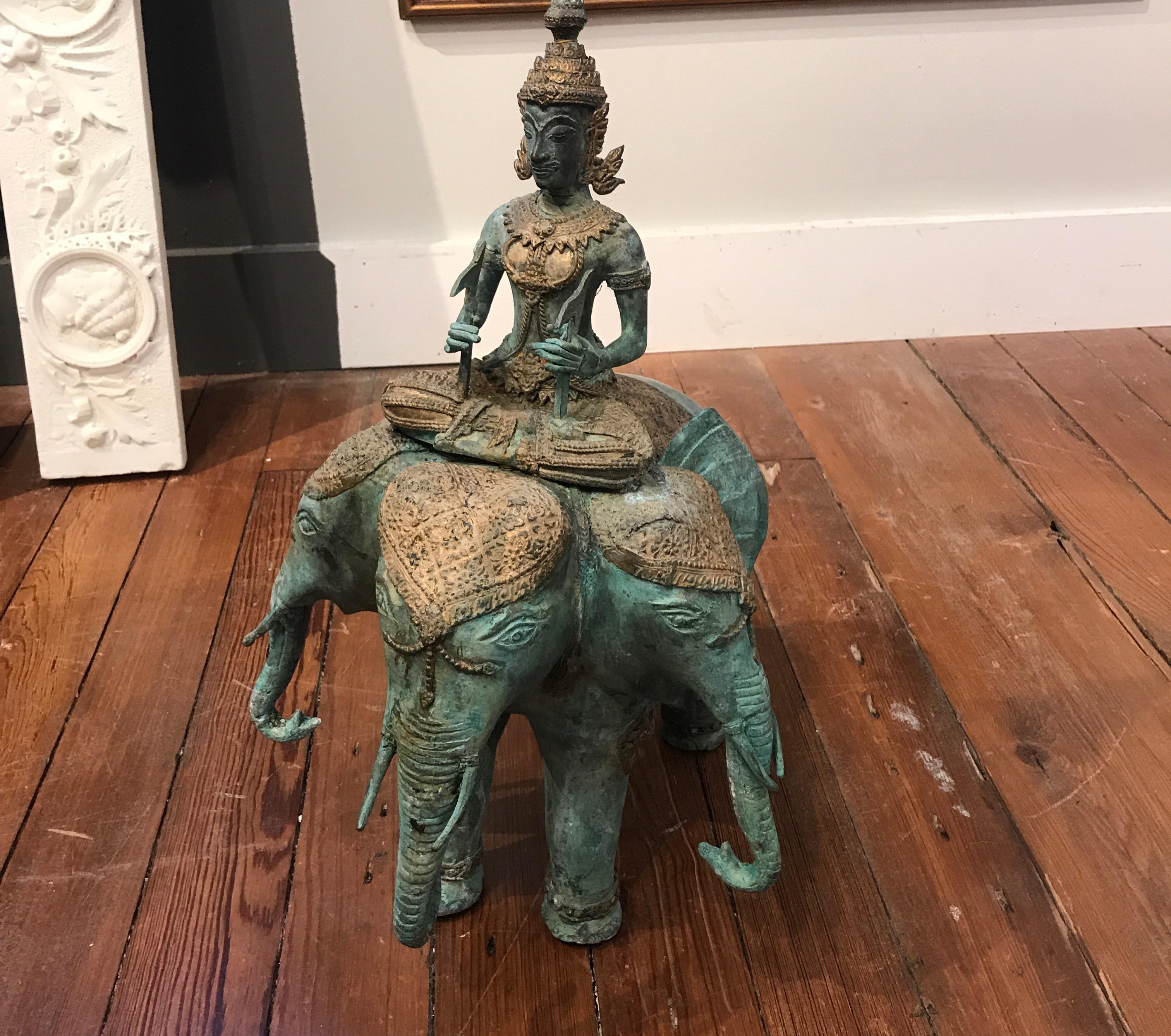 A oxidized aged finished bronze of a mythical three headed elephant with Buddha. The gilt details with a green aged oxidized patination.