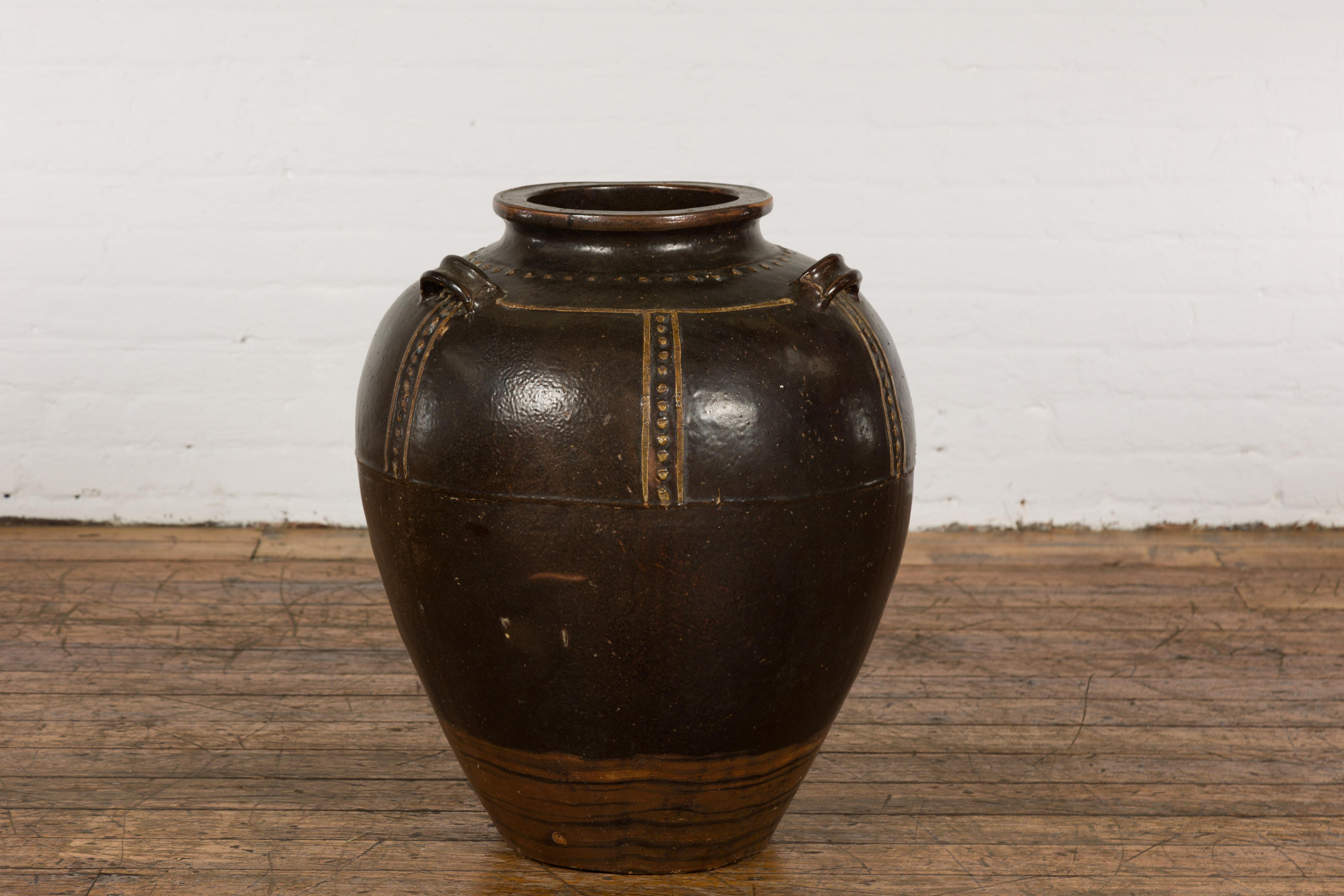 An antique Thai brown glazed ceramic vase from the early 20th century with petite loop handles, cream colored dotted décor, tapering lines and lighter brown accentuation. Experience a dash of Southeast Asian artistry with this charming antique Thai