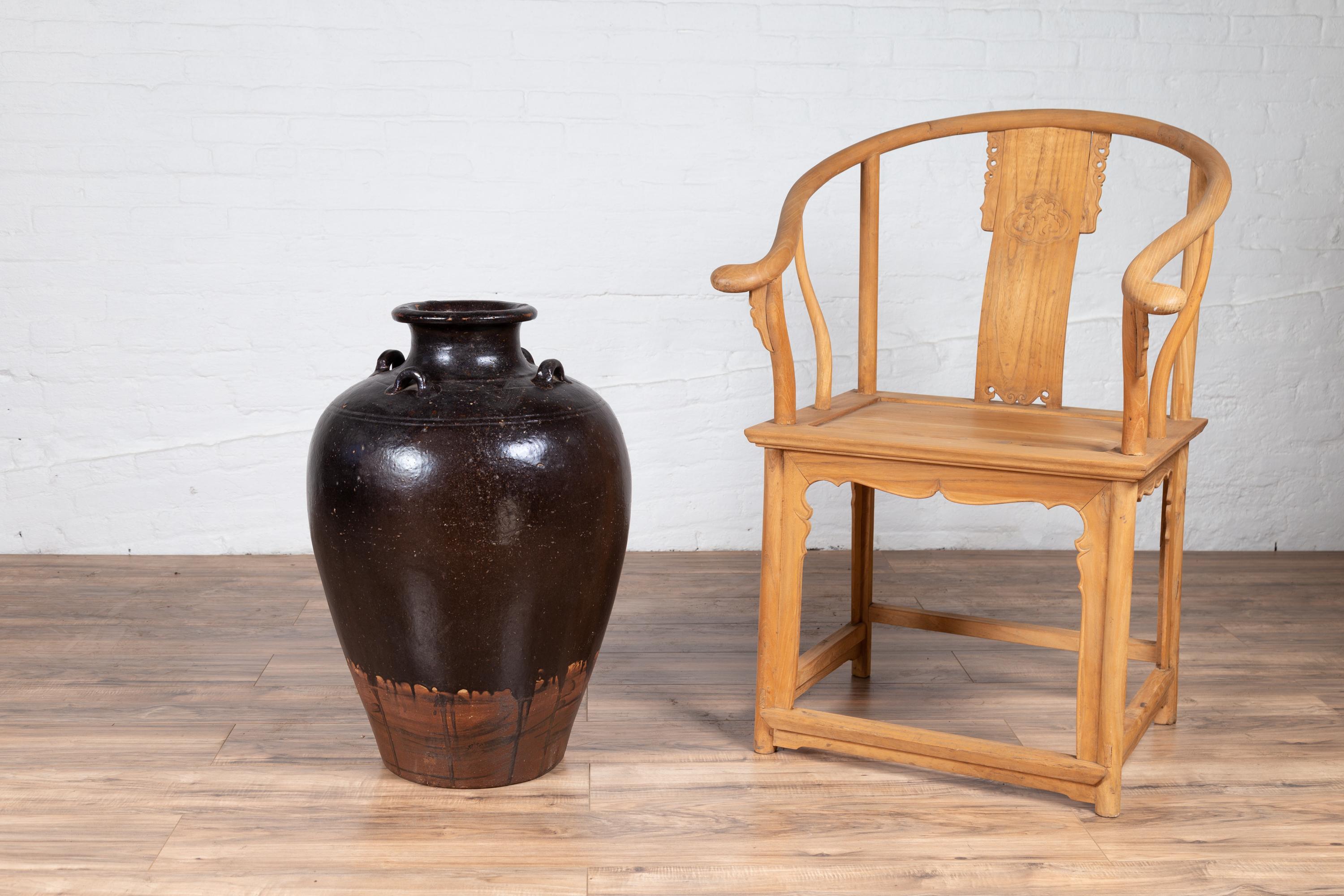An antique Thai monochrome brownware water jar from the early 20th century, with carrying handles. Born in Thailand during the early years of the 20th century, this charming water jug features a cylindrical tapering body boasting a monochrome