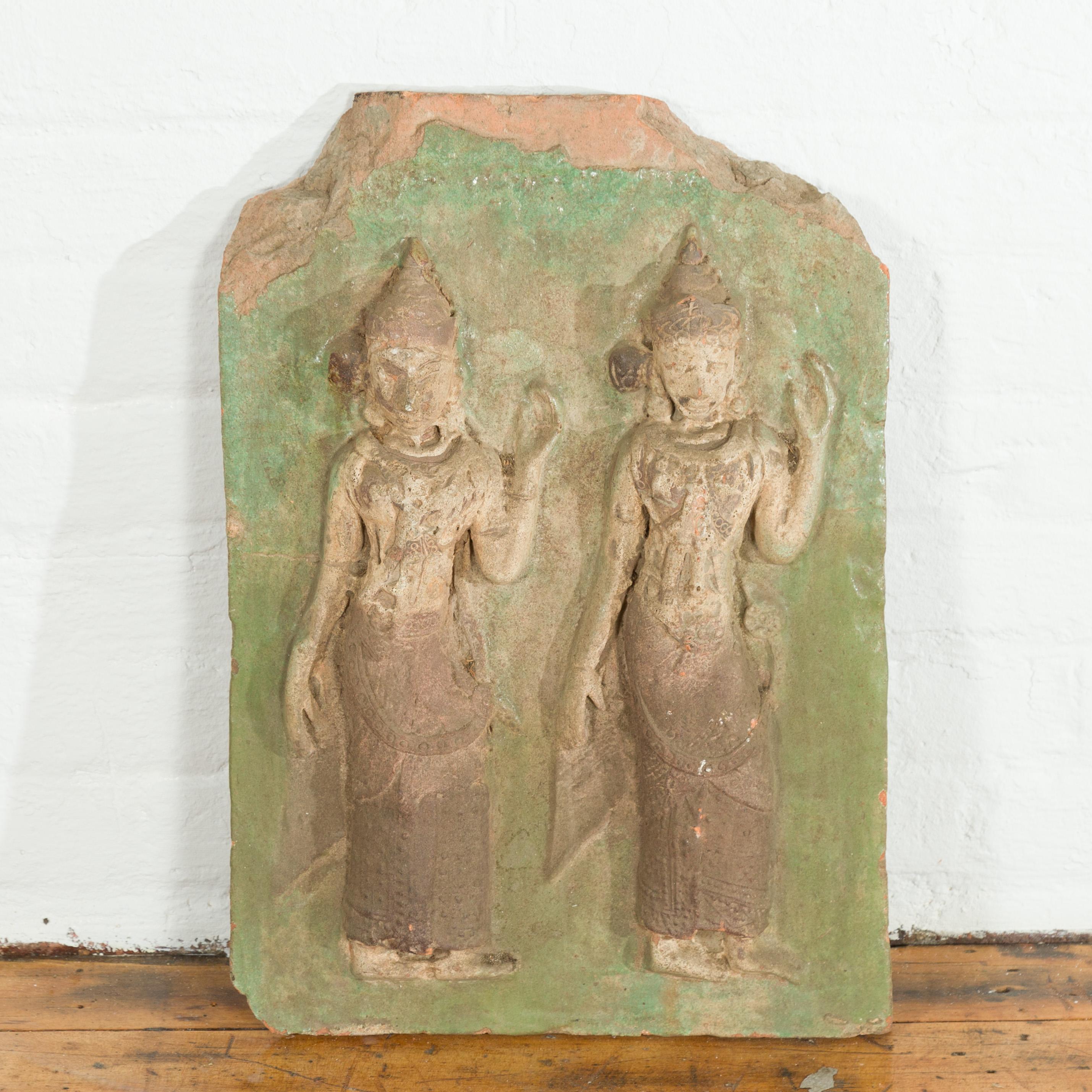 A Thai carved stone temple wall plaque depicting two ceremonial dancers with green accents. hand carved in Thailand, this antique wall plaque features a two ceremonial dancers with tall headdresses and long textured skirts, standing out beautifully