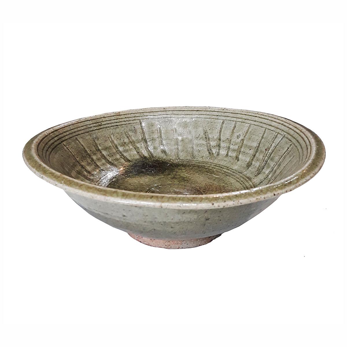 A Celadon bowl from the ancient kilns of Sangkhalok, one of the main centers of Thai ceramics during the Sukhotai period. Well preserved for its age, this plate shows the ancient technique of Celadon glaze, with its traditional green color and the