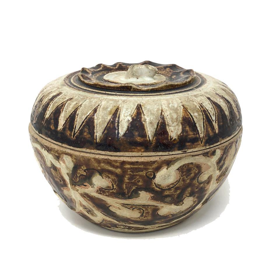 Caja de cerámica tailandesa con tapa, procedente de los hornos de Sawankhalok, de forma globular frutal con borde pellizcado foliado y remate de tallo en forma de sépalo en la parte superior, decorada con vidriado marrón y blanco con un diseño en