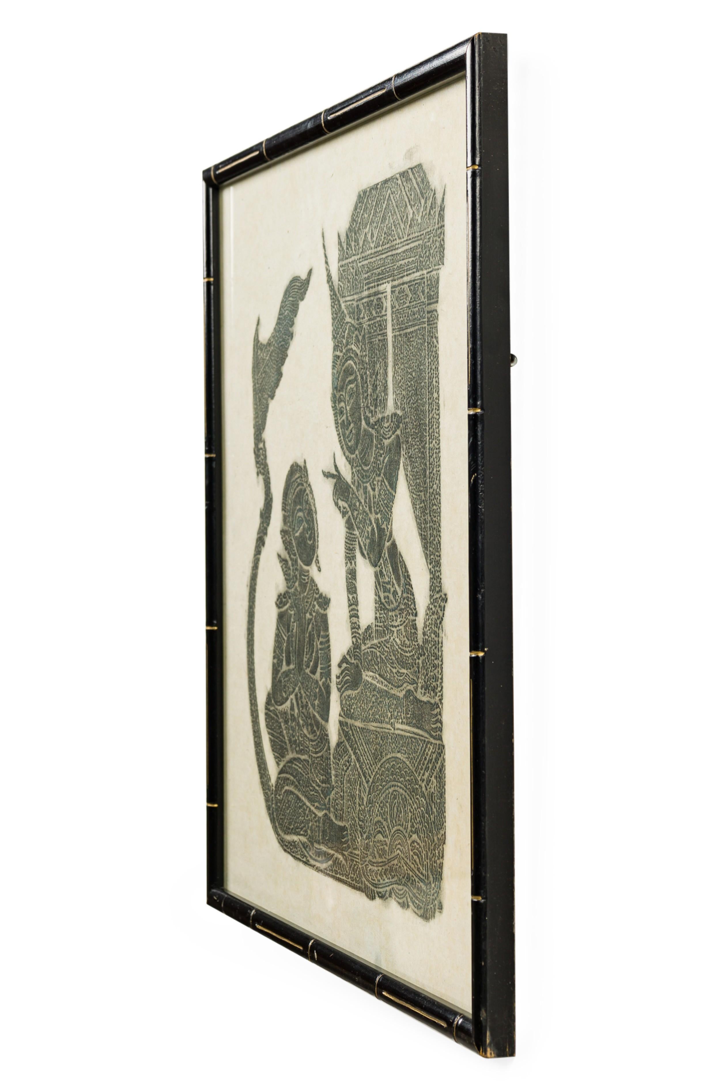 Fusain thaïlandais d'une scène avec des figures religieuses siamoises d'un homme et d'une femme assis dans un temple dans un cadre en faux bambou noir et doré (article similaire : NWL7051)