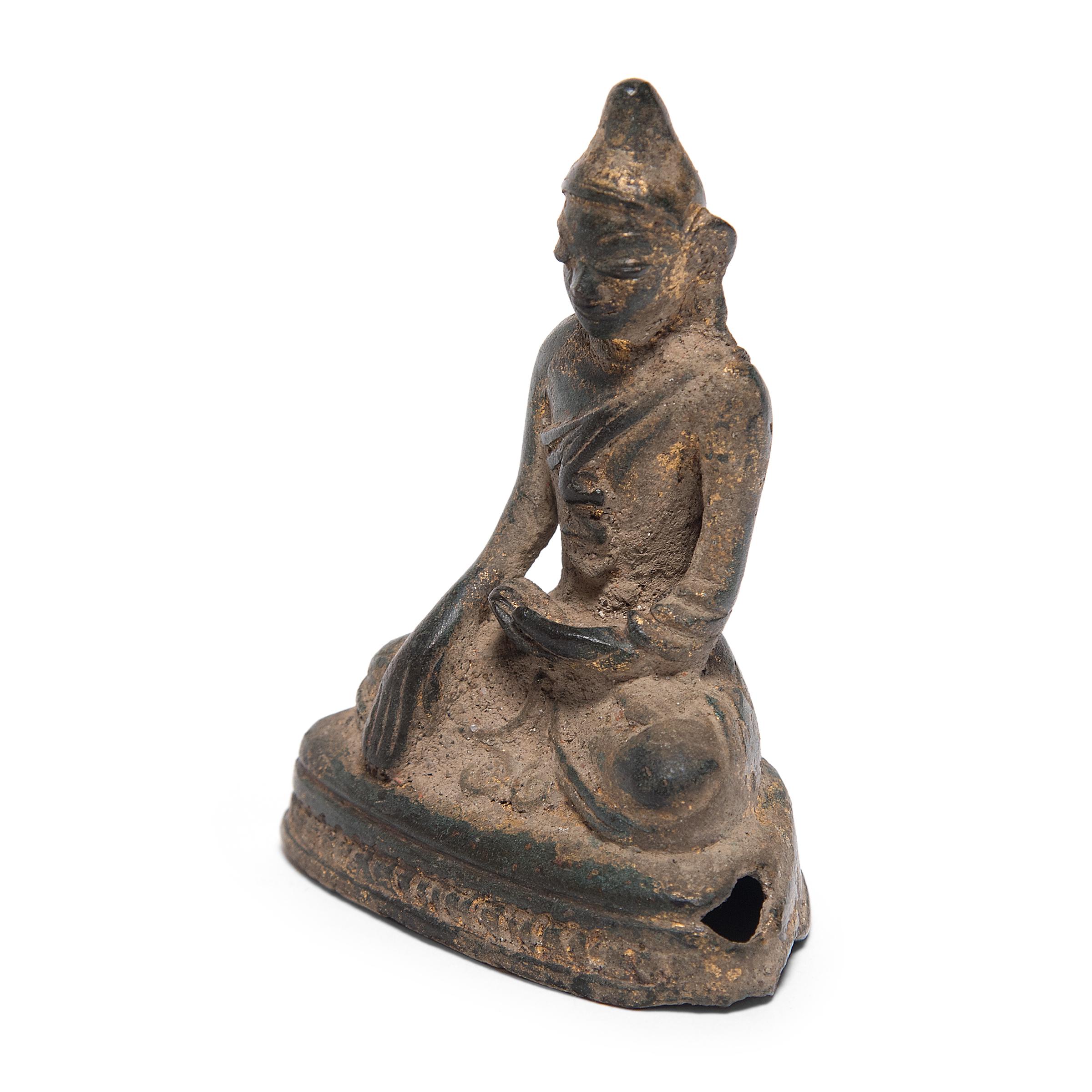 Once ornately gilt, this serene bronze seated Buddha was created in Thailand in the mid-19th century. Cast in the older Sukhothai style, the Buddha bears a uniquely Thai flame-like spike stretching upward from the crown of his head. Called an