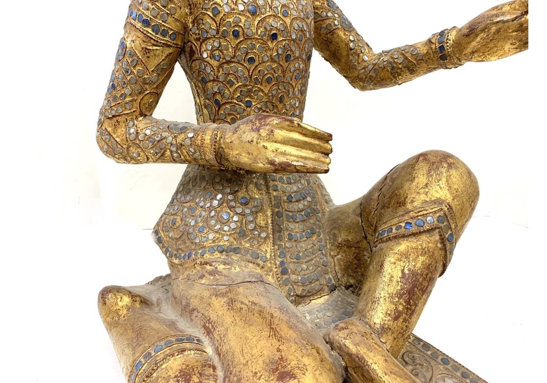 Large and weighty Thai gilt wood seated figure adorned and encrusted in multi-colored glass inlaid mosaics.
Dimensions: 13 1/2