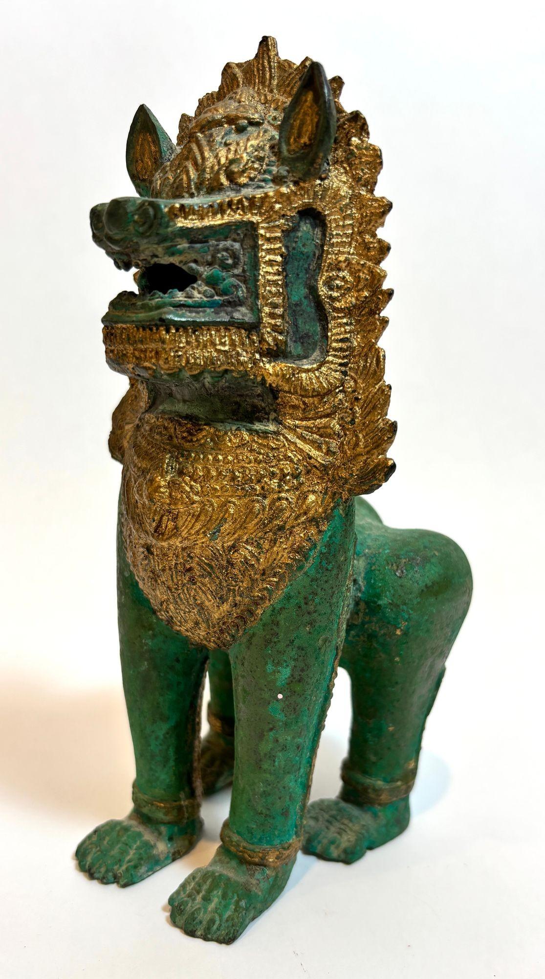 Thai Khmer Bronze Gilt Singha Guardian Lion Sculpture, Mid-20th Century
An exquisite Thai–Khmer bronze Singha guardian lion, also referred to in the West as a Foo Dog, richly decorated with parcel-gilt accents over a naturally aged verdigris