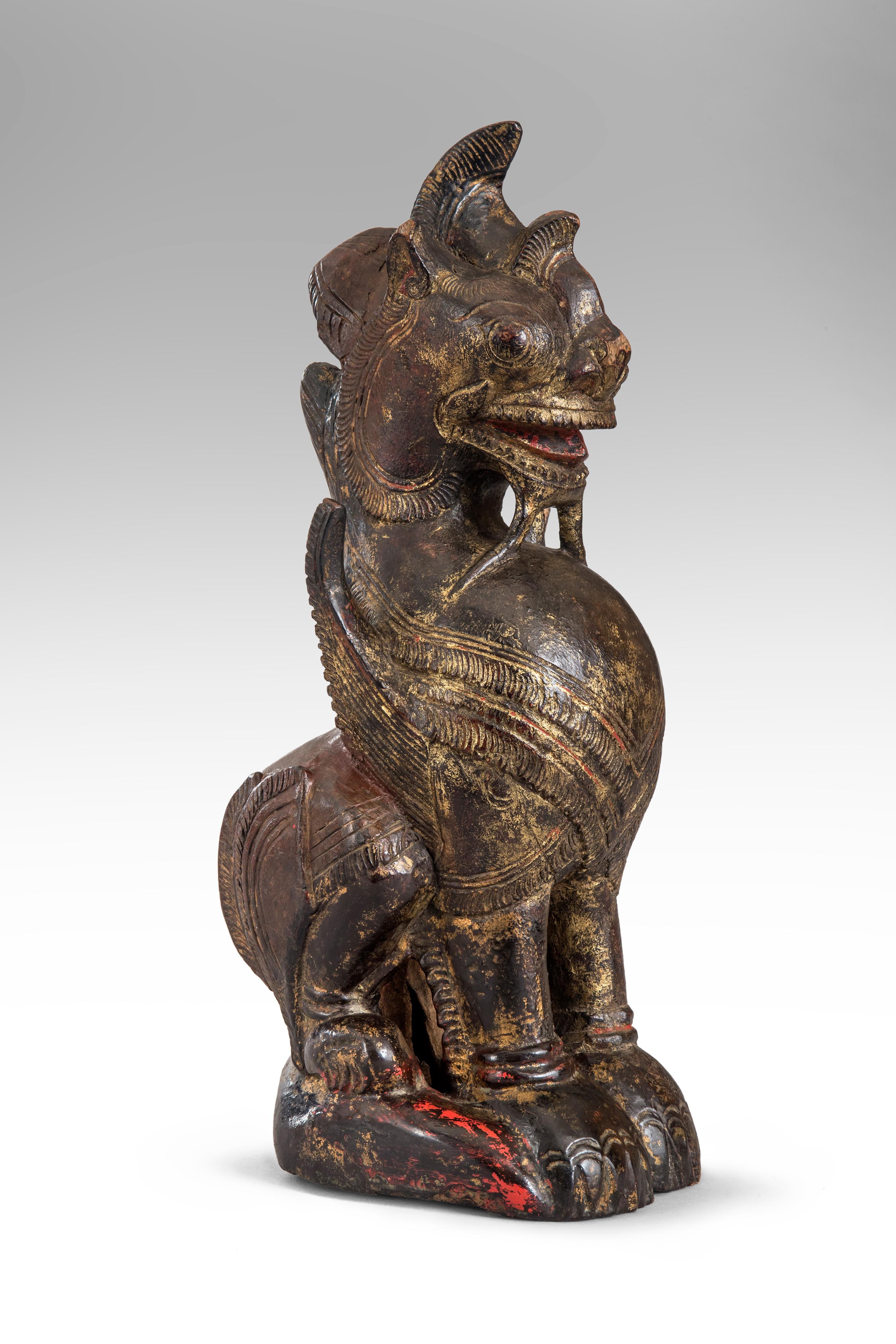Thailändische mythologische Wächterlöwen-Skulptur
19. oder 20. Jahrhundert.
Die gut geschnitzte, aufrecht sitzende geflügelte Figur mit gealterter schwarzer und roter Farbe, Spuren von Vergoldung. Kleiner Teil des Sockels fehlt, sonst in