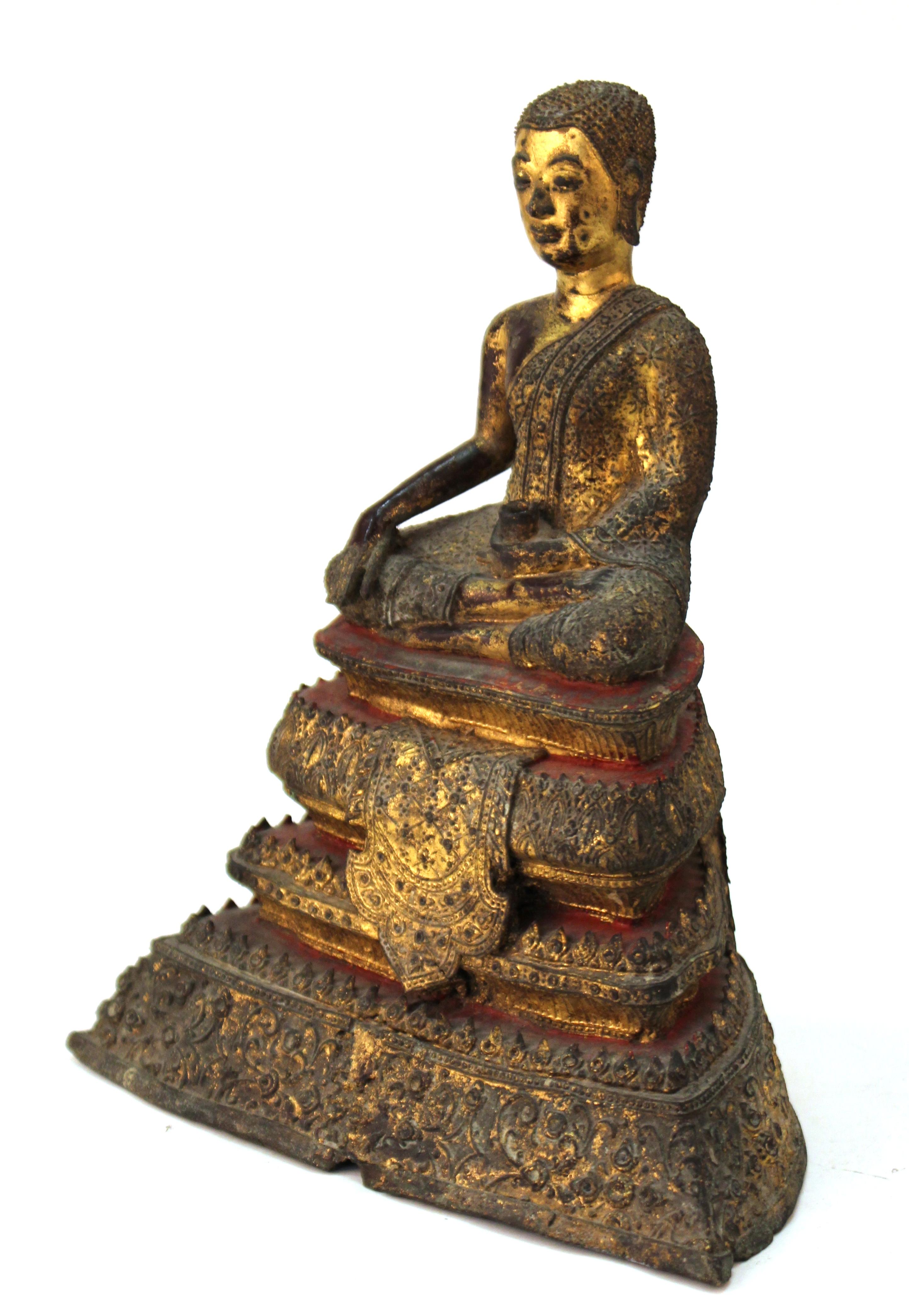 Thai Rattanakosin period cast gilt bronze Buddha from the mid-19th century, seated on a multi-tiered throne base. The backside of the statue has rings to be used as attachments to secure it to a wall within a temple setting. The statue is in great