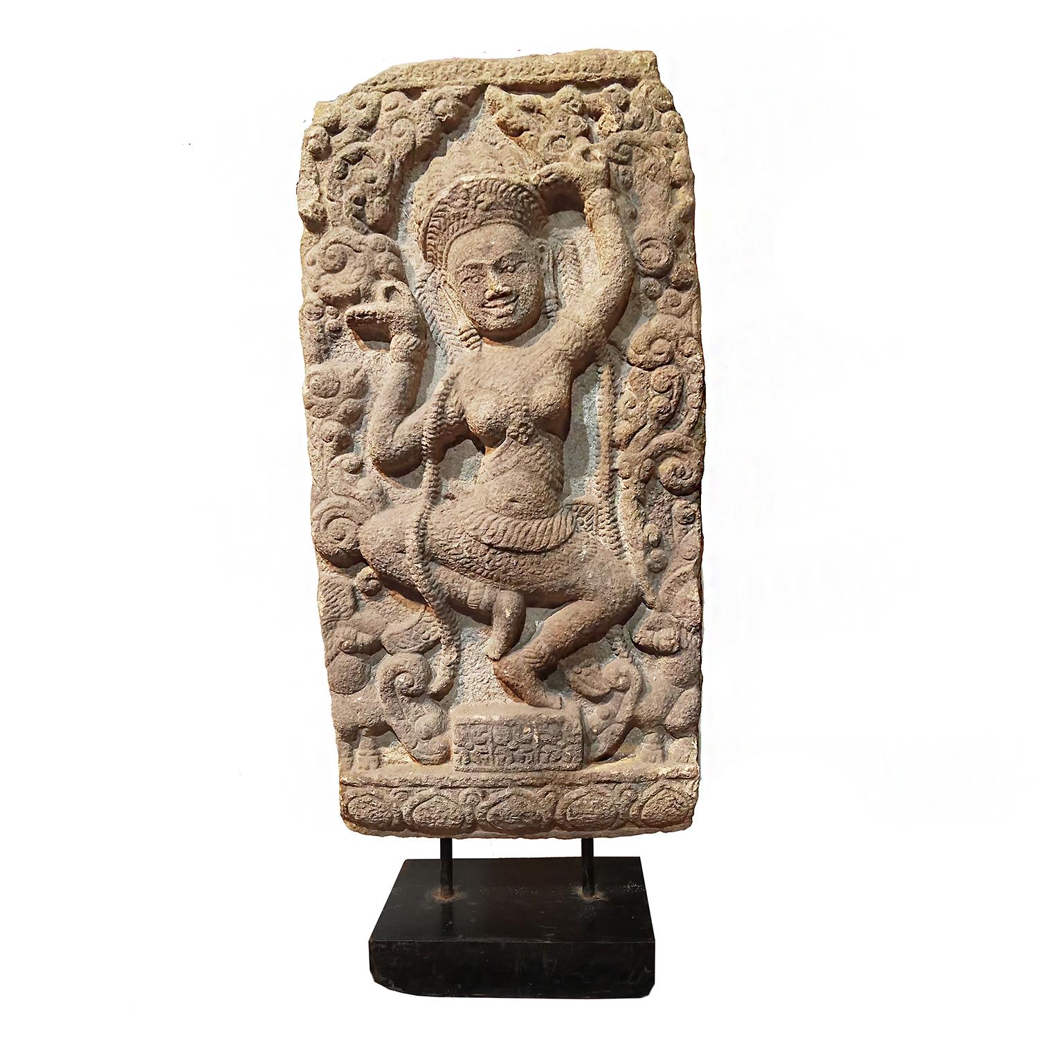 A stone relief of a dancing goddess, crafted in Thailand, late 20th Century. 

Hand-carved from a solid piece of amber-colored sandstone. 26.5 inches high, 3 inches deep, 12 inches wide. The carving is mounted on a 5