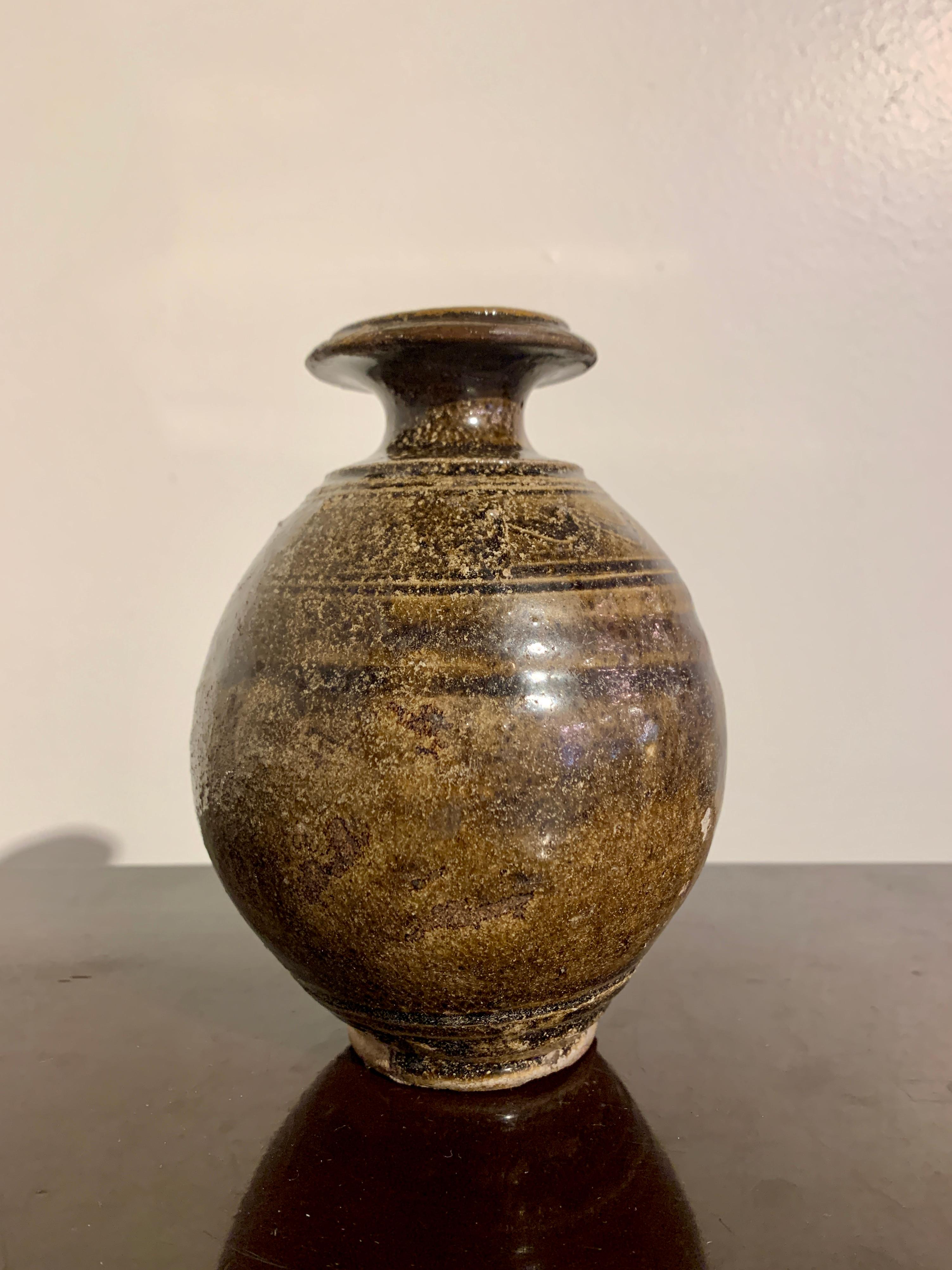 A lovely Thai Sawankhalok small bottle vase with olive and brown glaze, 14th to 16th century, Ayutthaya Period, Thailand.

The stoneware vase of globular form, set on a short foot with a narrow neck and flared mouth. The shoulders decorated with