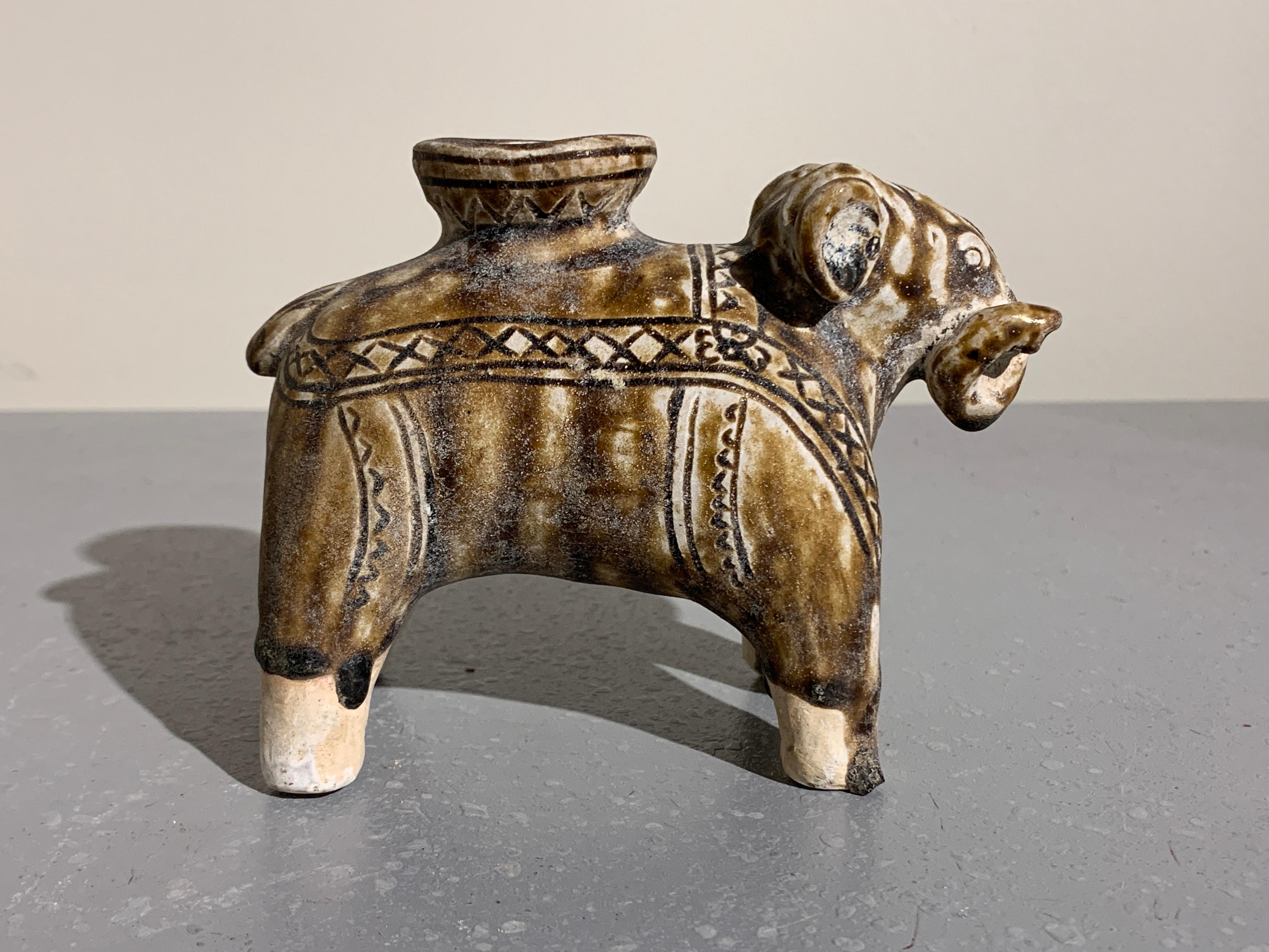A charming Sawankhalok brown glazed figure of an elephant, Sukhothai Period, Thailand, early 14th century.
The cartoon-like elephant stands foursquare on stout legs, looking straight ahead. His trunk and tail are both curled to one side, with his