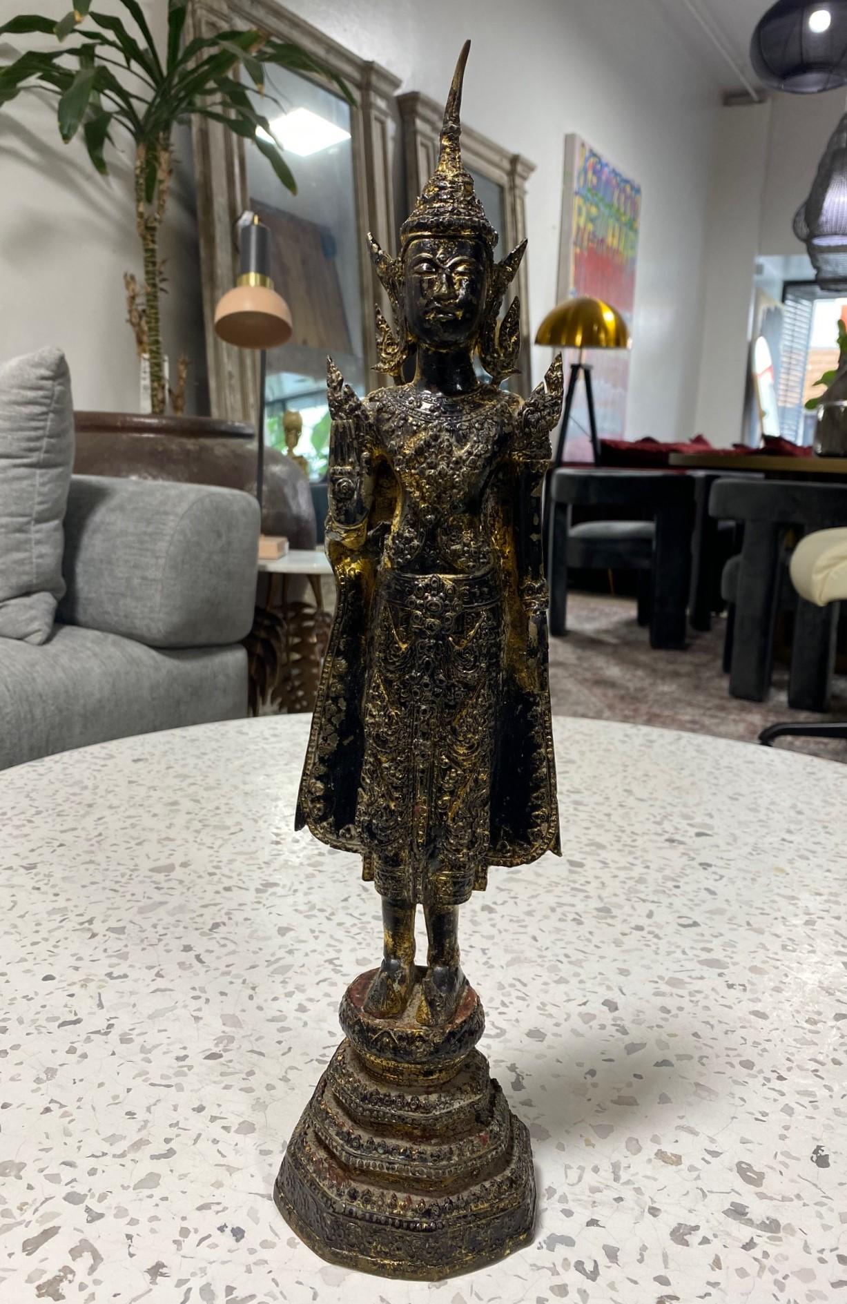 A wonderful piece. This beautifully sculpted and adorned bronze and gilt, Buddha is from the Thai Rattanakosin Kingdom period (1782-1932) and has a nice patina and coloring acquired through age. The Buddha is in a standing position and is holding