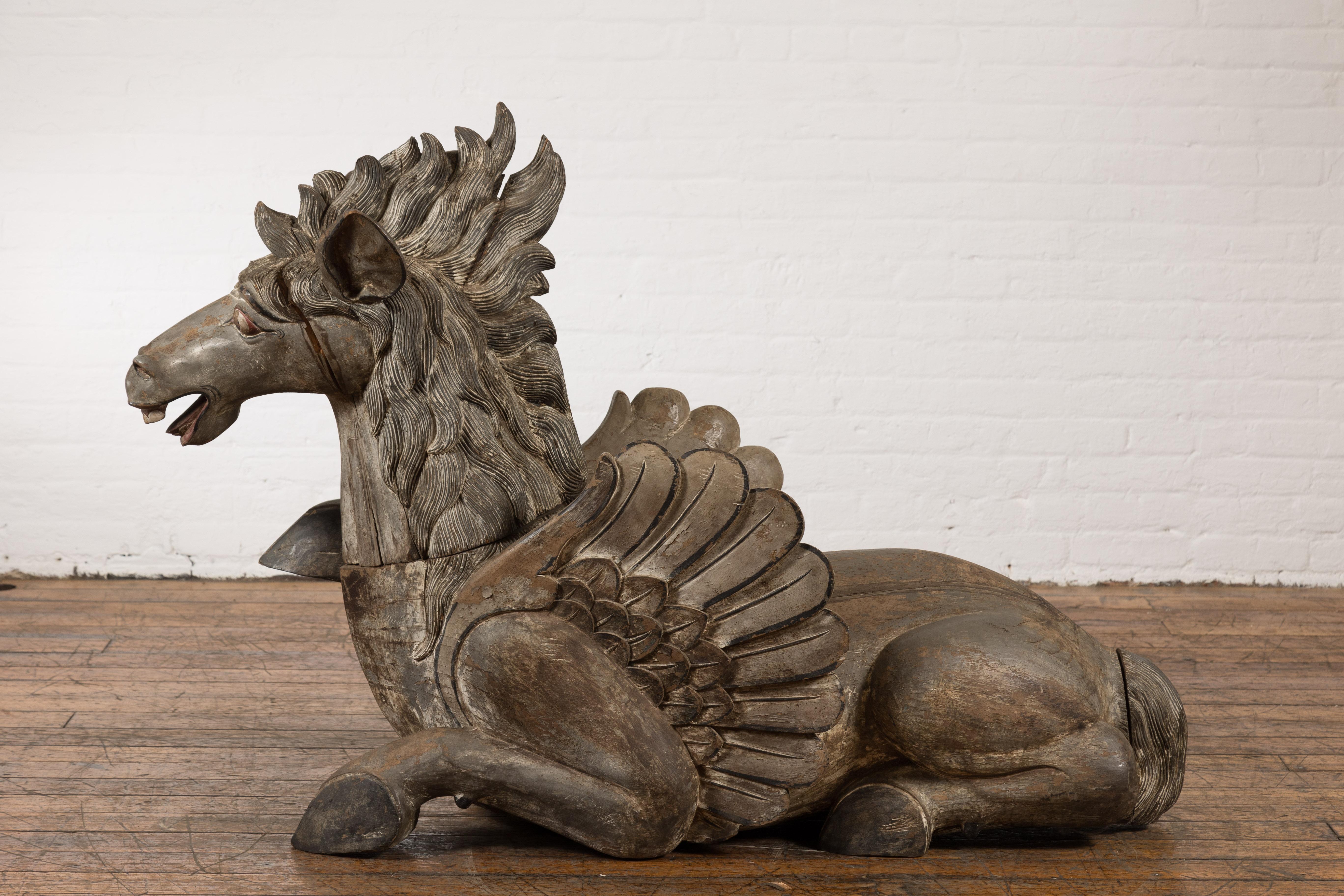 A vintage Thai carved and painted wooden winged horse from the mid 20th century, with nicely detailed mane, striking facial expression and weathered appearance. Exuding an ethereal charm, this vintage Thai wooden winged horse sculpture from the