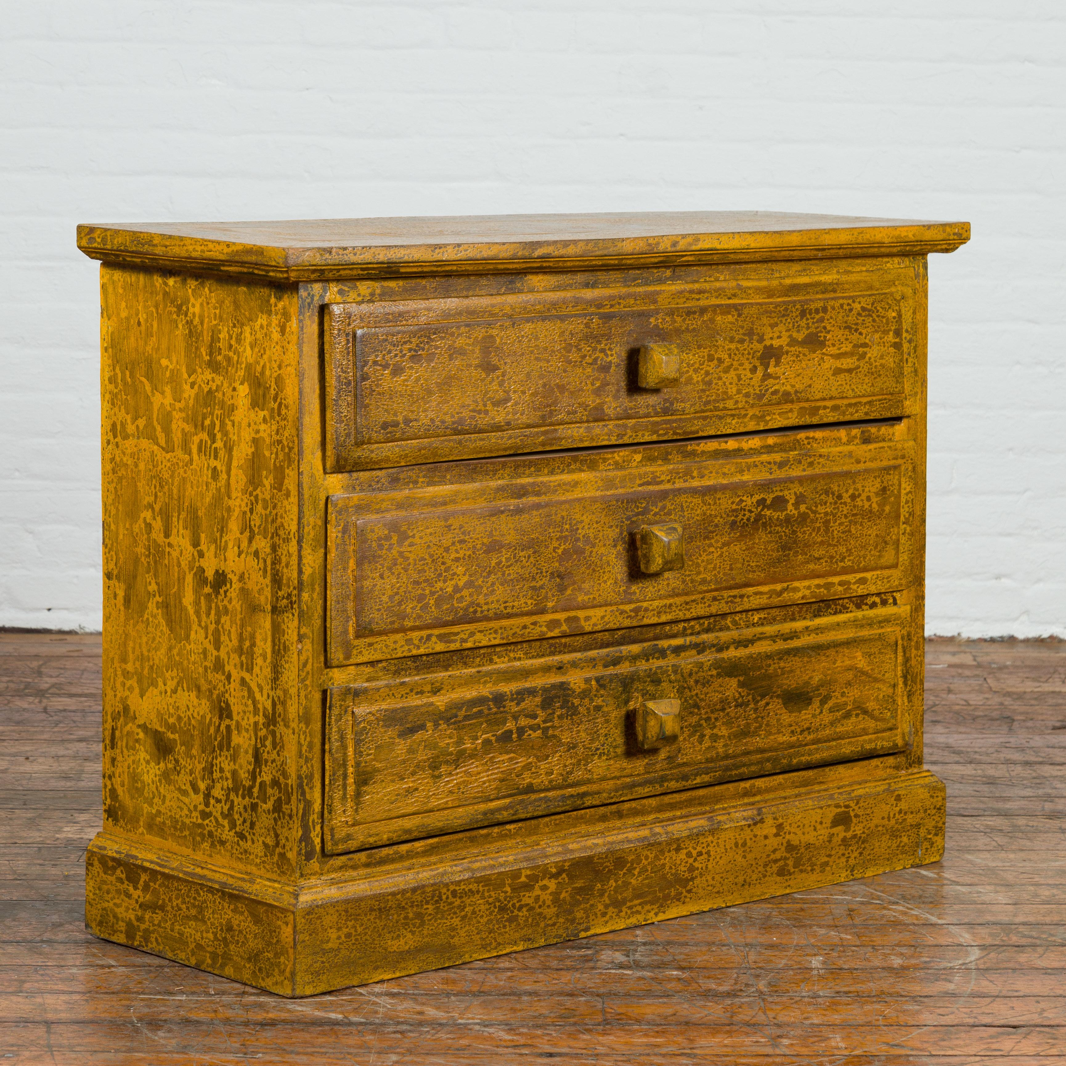 A stunning addition to our vintage furniture collection, this mustard colored glazed side chest from Thailand is an eye-catching piece with its yellow and brown lacquered color. This vintage side chest from the mid 20th century showcases a