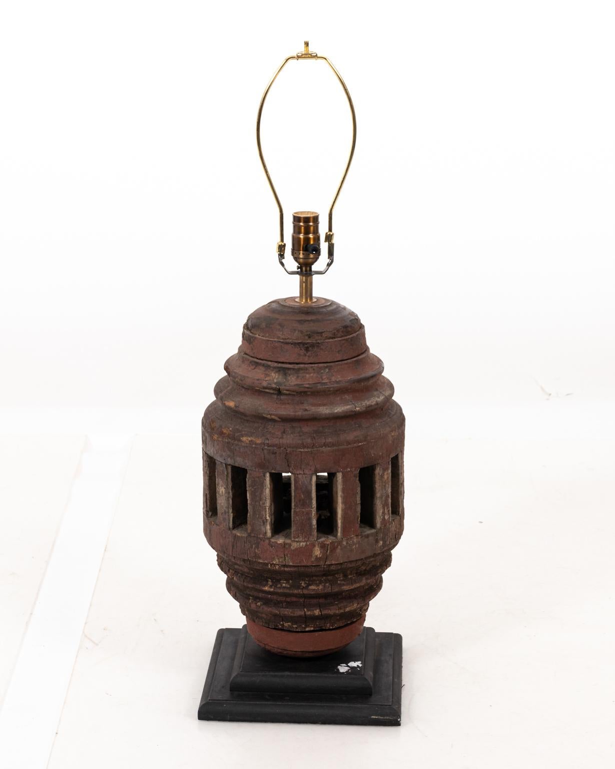 Thai wood cog covered table lamp on black painted wood plinth, circa 1960s. The piece also features a black Belgian shade with black wood finial. Please note of wear consistent with age including heavy finish loss, evidence of cracks, and wood loss