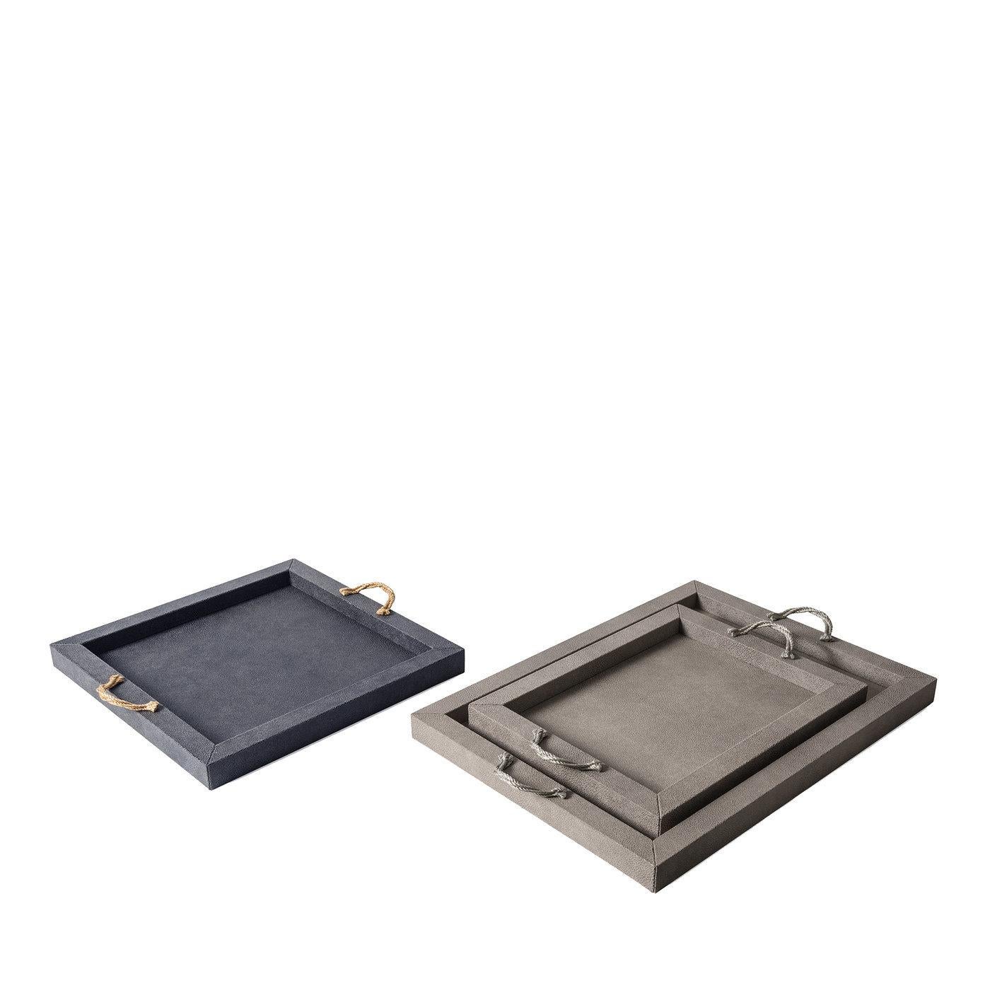 Esta bandeja, que forma parte de la Colección Thalia, es una celebración del minimalismo y la sofisticación. Fabricada en madera con base antideslizante, su silueta rectangular está revestida de cuero de un elegante color gris que complementa el