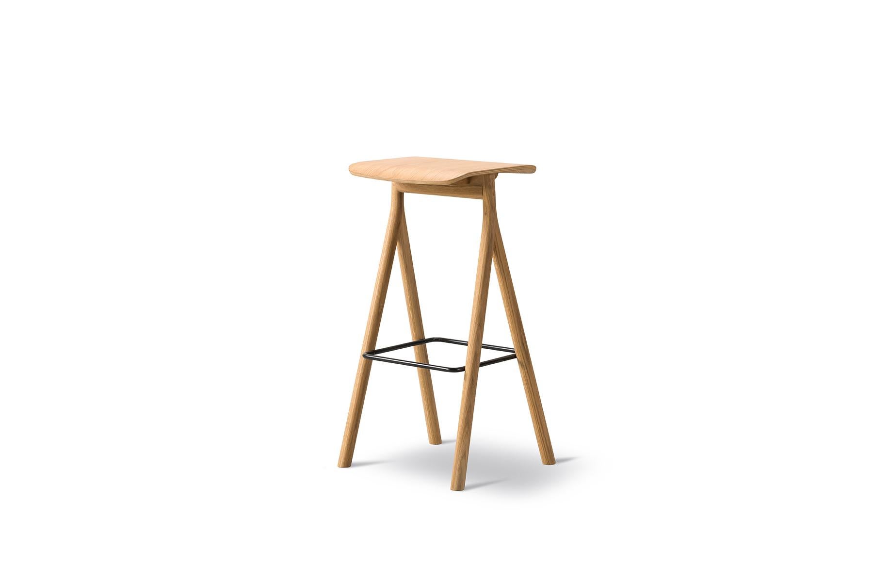 The Thau + Kallio Yksi barstool stands strong yet appears light with its signature Y-shaped legs positioned upside-down. Crafted from solid oak and available in lacquered or black lacquered oak, the impression is minimal with maximum attention to