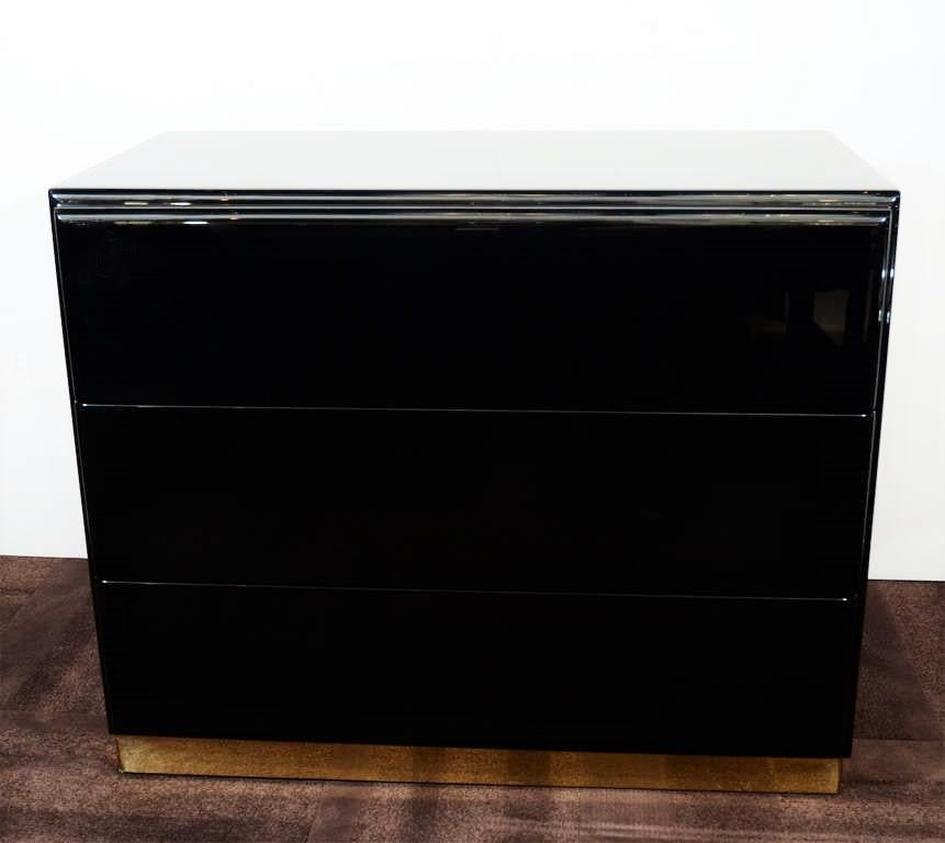 Amazing pair of large nightstands or chests by Thayer Coggin. Freshly lacquered in black. Each chest is fitted with three spacious wood drawers on a brass plinth base.