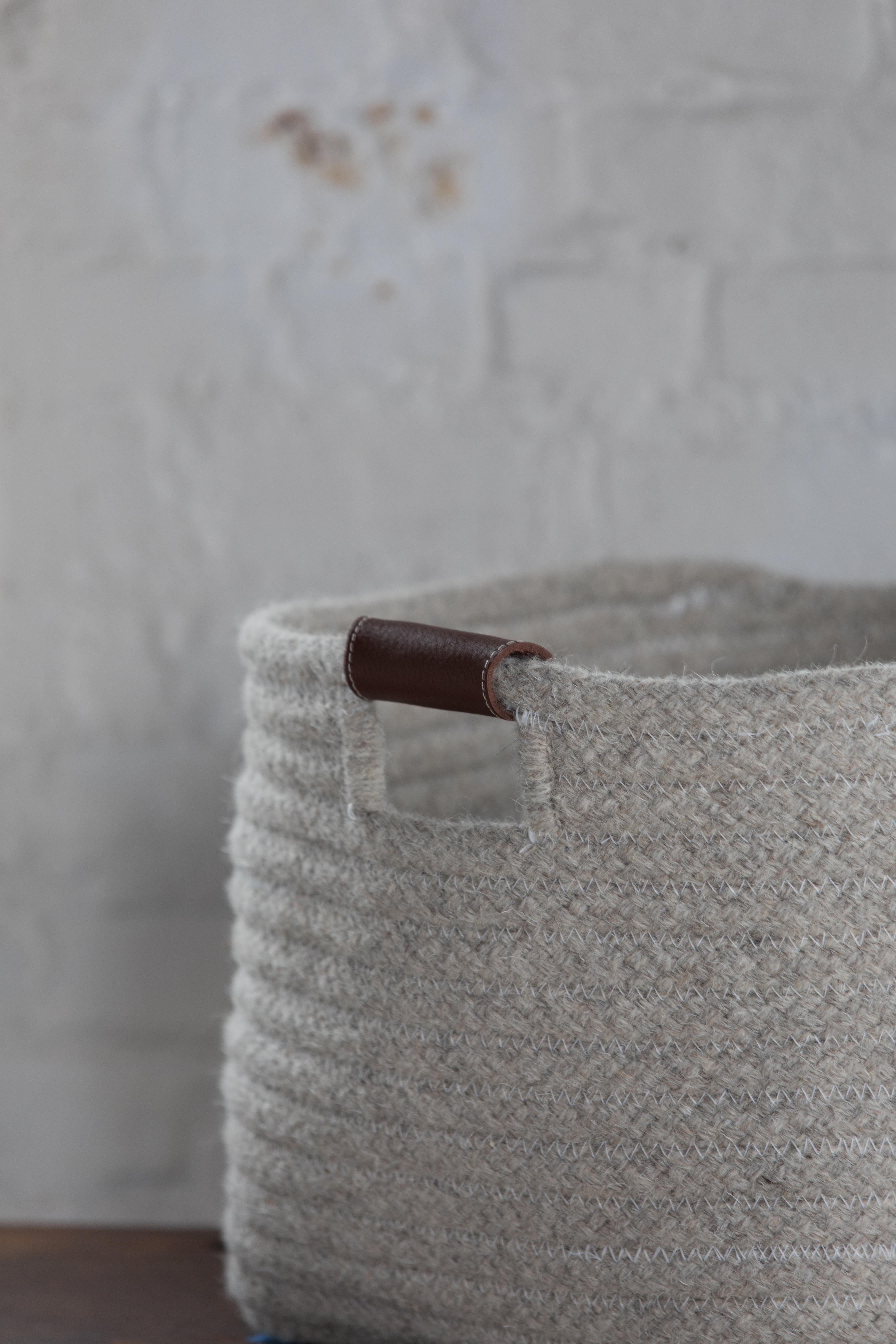 Simple and sturdy woven basket in a rectangle design. Light grey, natural un-dyed wool is accented with leather handles. Handle color options are brown, black, and natural. 

Designed by Meredith Thayer in her South Boston studio and made to order