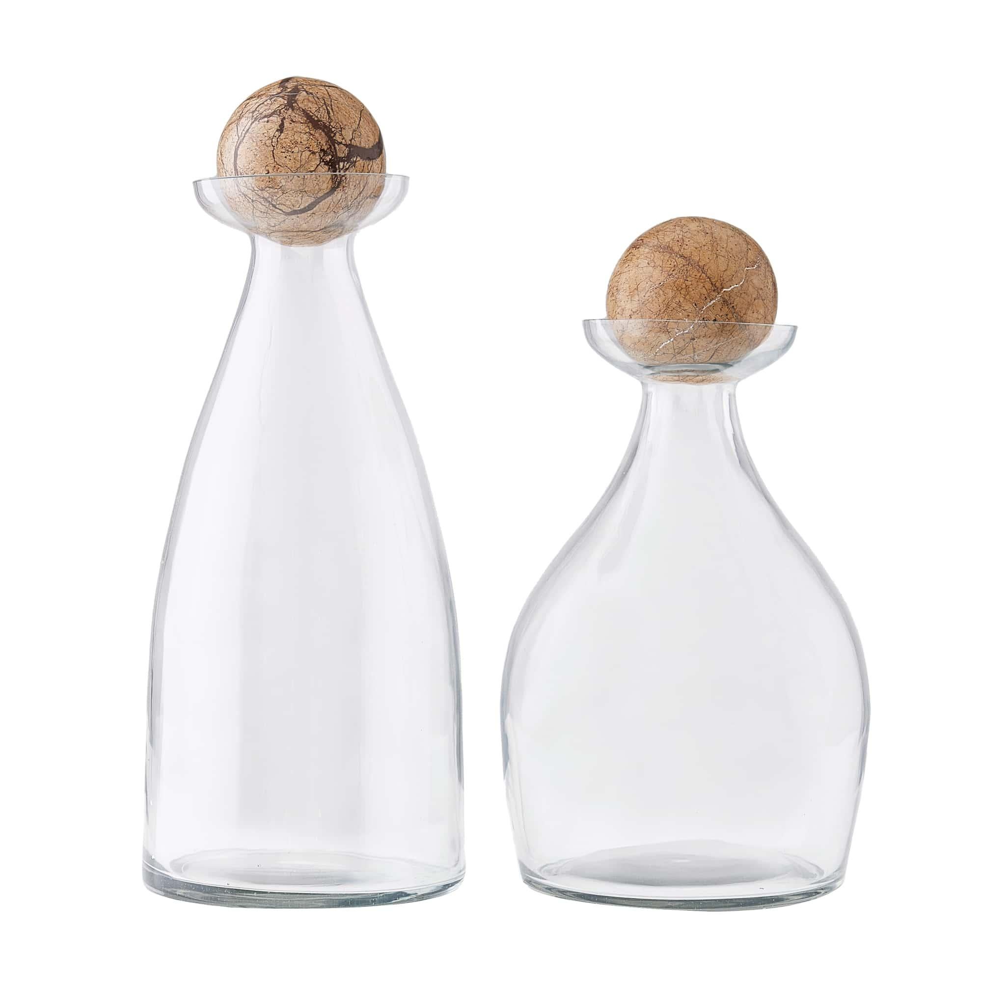 Offered as a pair in two distinct sizes, these elegant clear glass Thayer decanters bring sculptural beauty and versatility to any interior. Each vessel is crafted with an amorphous, organic shape that gently curves into an extended mouth—an
