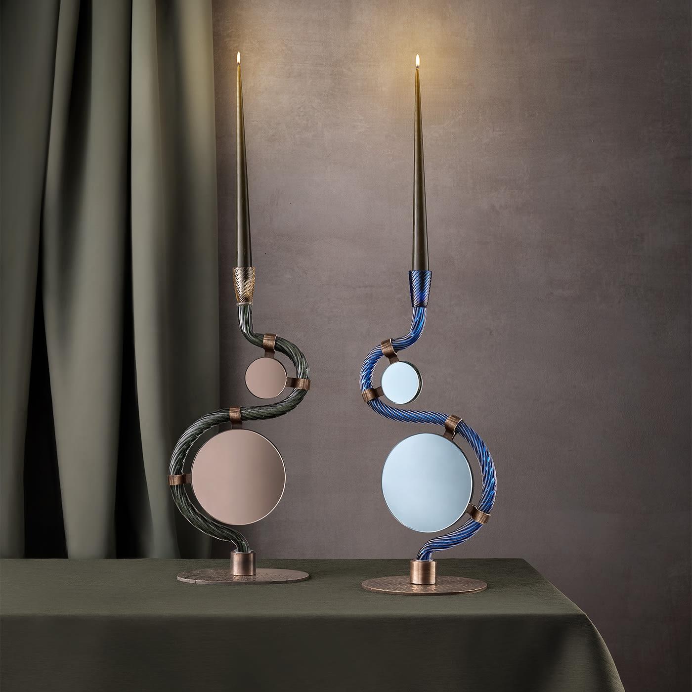 The vertical mirrors and deep blue Murano glass candleholder in this collection represent Aina Kari's deep connection to Venetian heritage and meaningful design. The sinuous, mouth-blown deep blue glass, with its four hammered brass 
