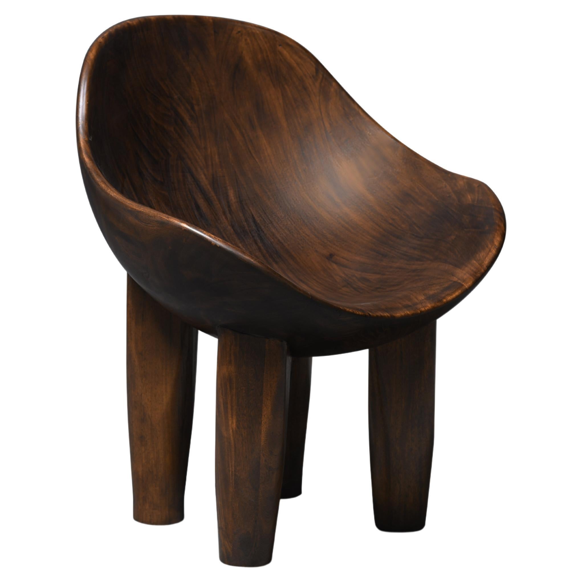 La chaise Aman est entièrement sculptée en bois massif avec une forme concave en vente