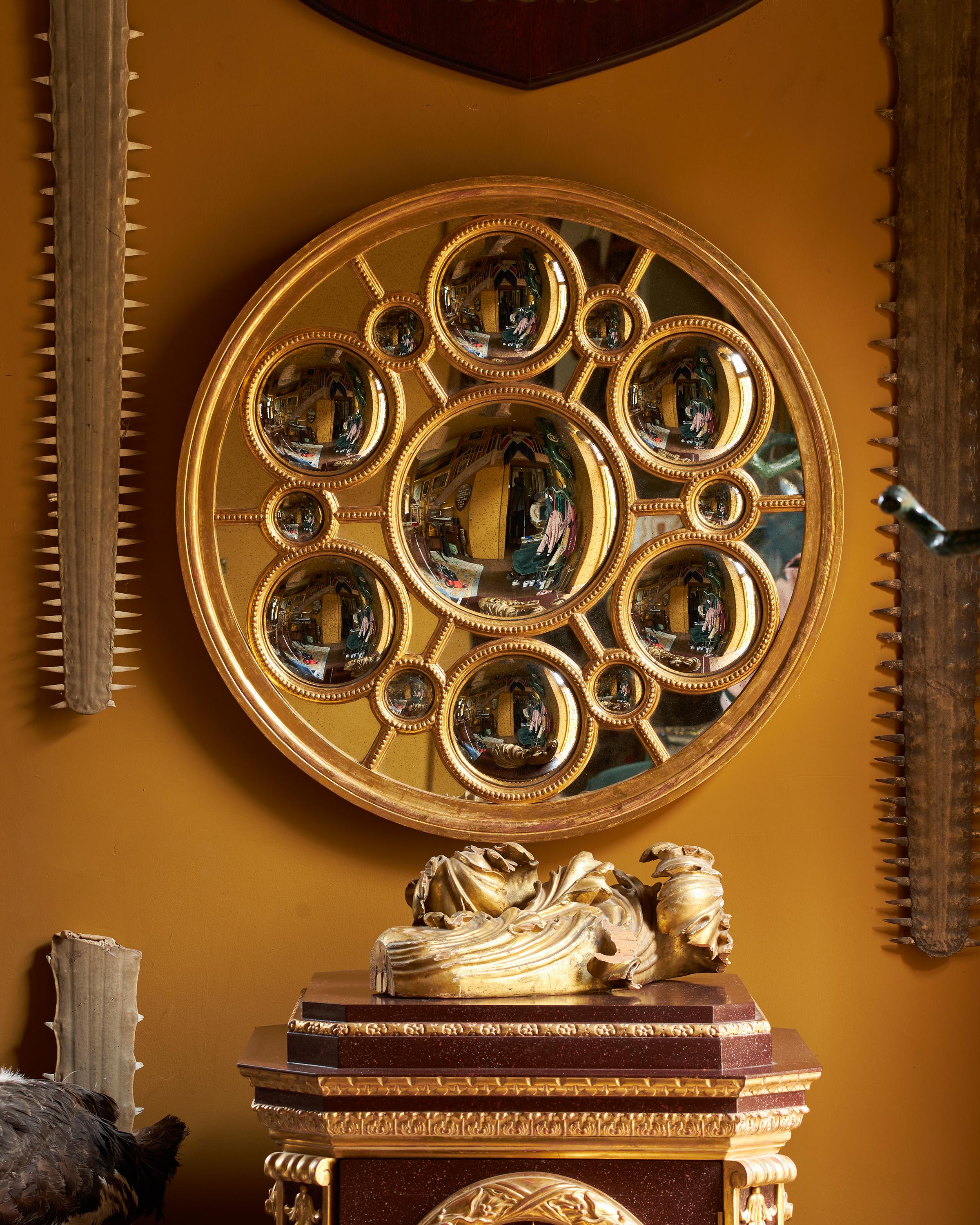 A fine circular giltwood architectural looking glass mirror. The looking glass includes an impressive forty-three different aged mirror plates, thirteen of them round convex glasses. The mirror with simply moulded edge and curved beading detail