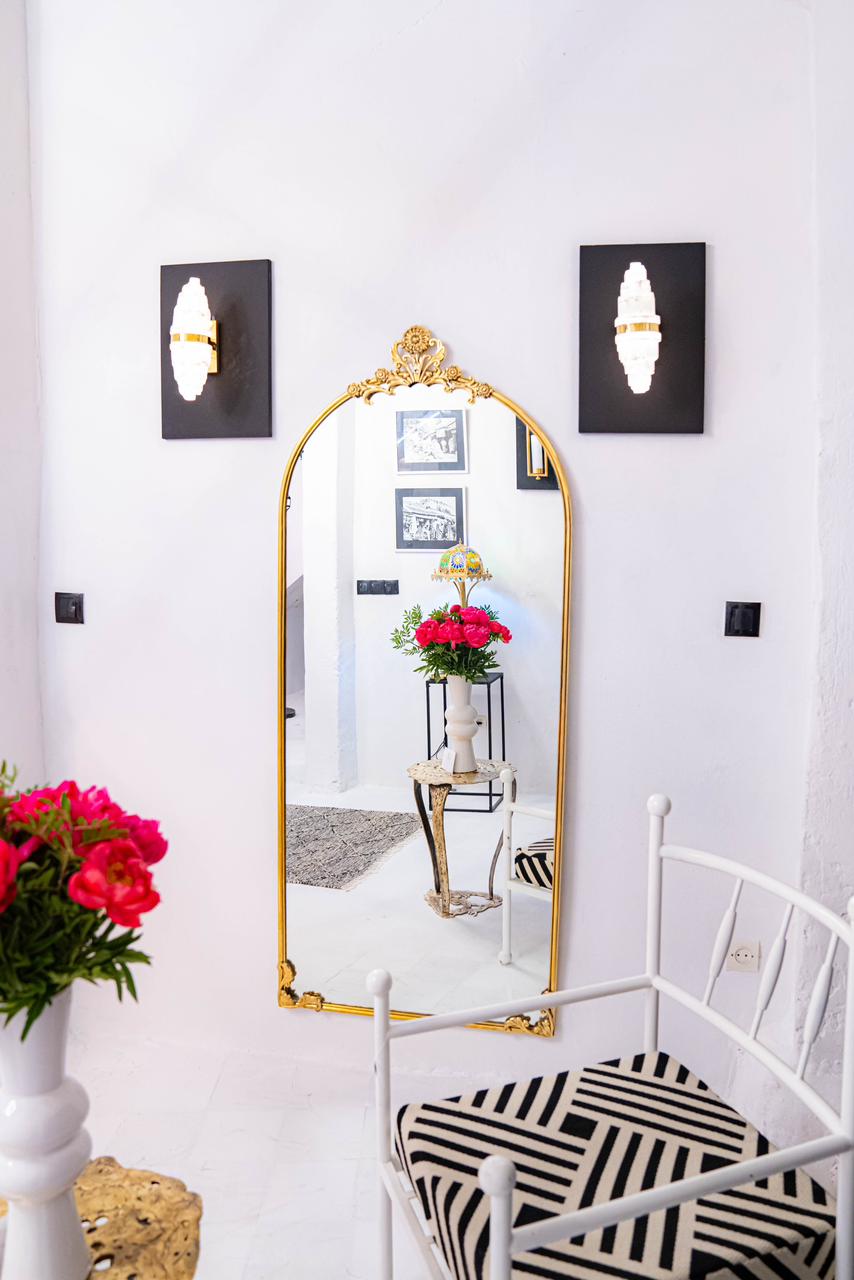 This elegant brass mirror is inspired by the refined aesthetic of French Neoclassical design. It features a slender 2 cm frame, adorned with delicately cast brass details — a graceful floral motif crowning the top, and ornate L-shaped embellishments