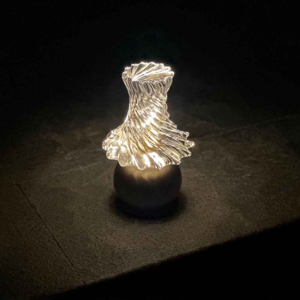 inspirée par les lumières dansantes et l'aura mystique de ce spectacle naturel, l'aurore présente un cristal massif cannelé sculptural, rappelant les méduses lumineuses. élégamment associée à un socle en bronze sculpté, cette pièce vous invite à