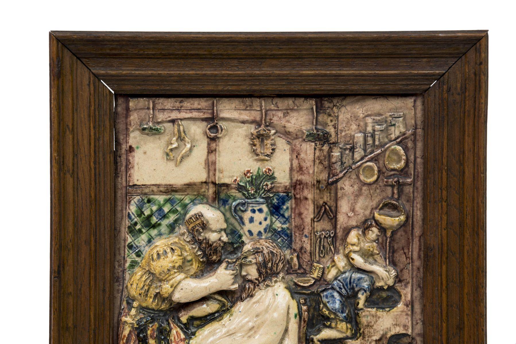 This ceramic plaque was made at the end of the 19th century by the Landais workshop. It depicts the interior of a barbershop while a customer is getting his hair done. in the background, we can see a barber washing the hair of another man. The scene