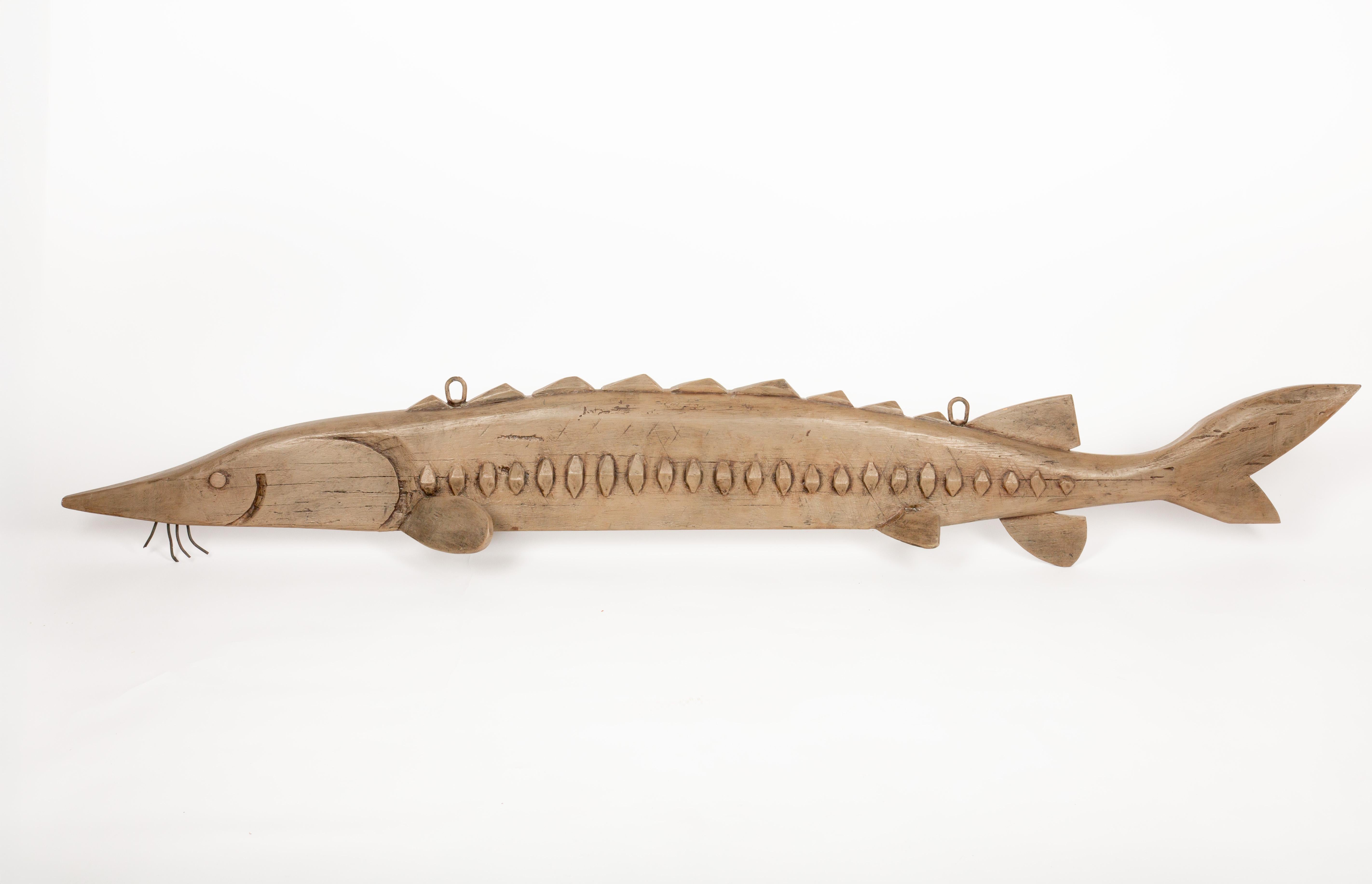Este esturión de madera del río Hudson, de arte popular y tallado a mano, es una pieza excepcional de Jeff Raymond (1949-2022, Poughkeepsie y Red Hook, NY), artista autodidacta conocido por su pasión por la fauna marítima y del río Hudson. Con unas