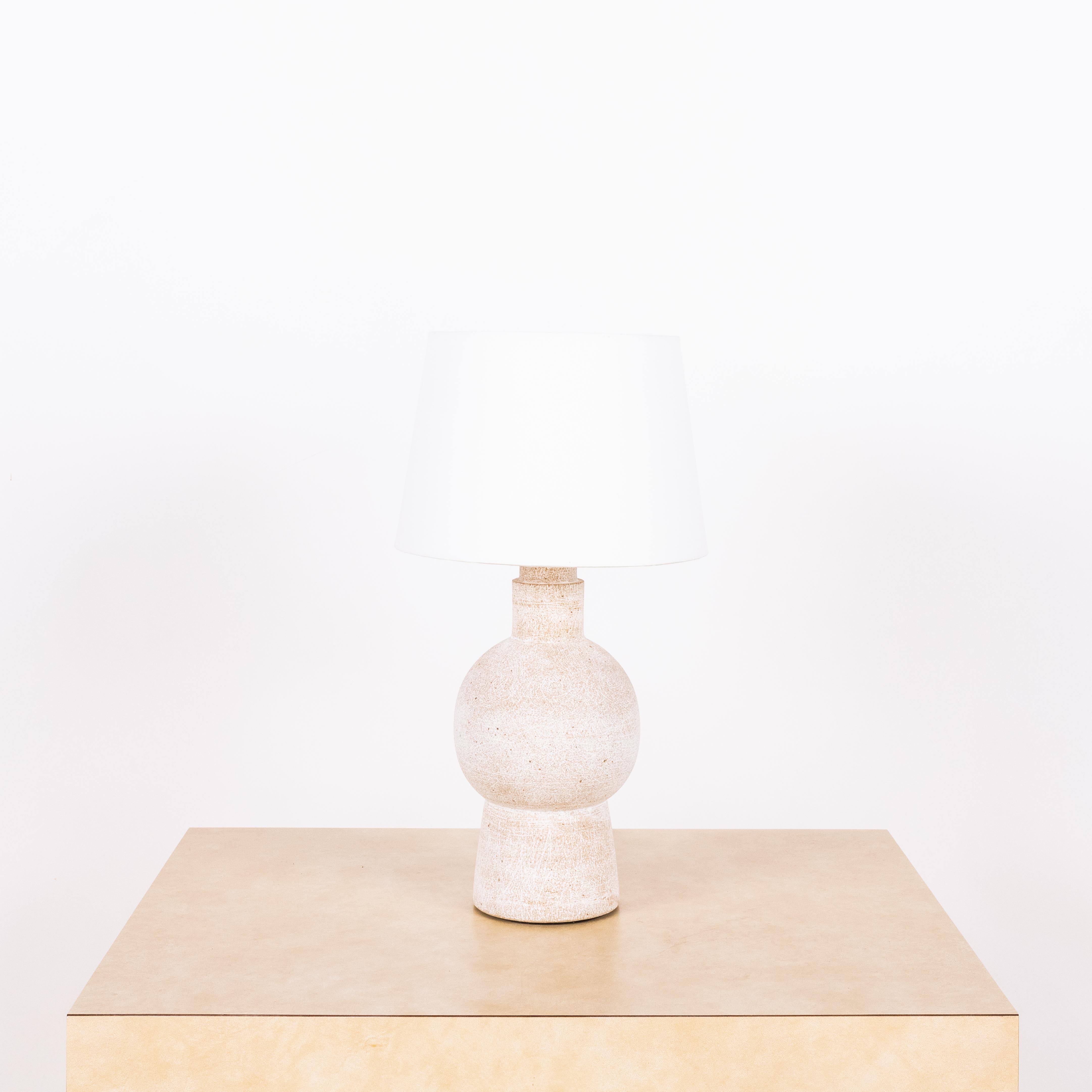 White 'Bilboquet' stoneware lamp by Design Frères.

Dimensions listed (10 in. diameter x 18 in. tall) are the overall dimensions of the lamp plus the shade (as pictured). The lamp base is 11 in. tall and the shade is 7 in. tall.

Wired with 3-way