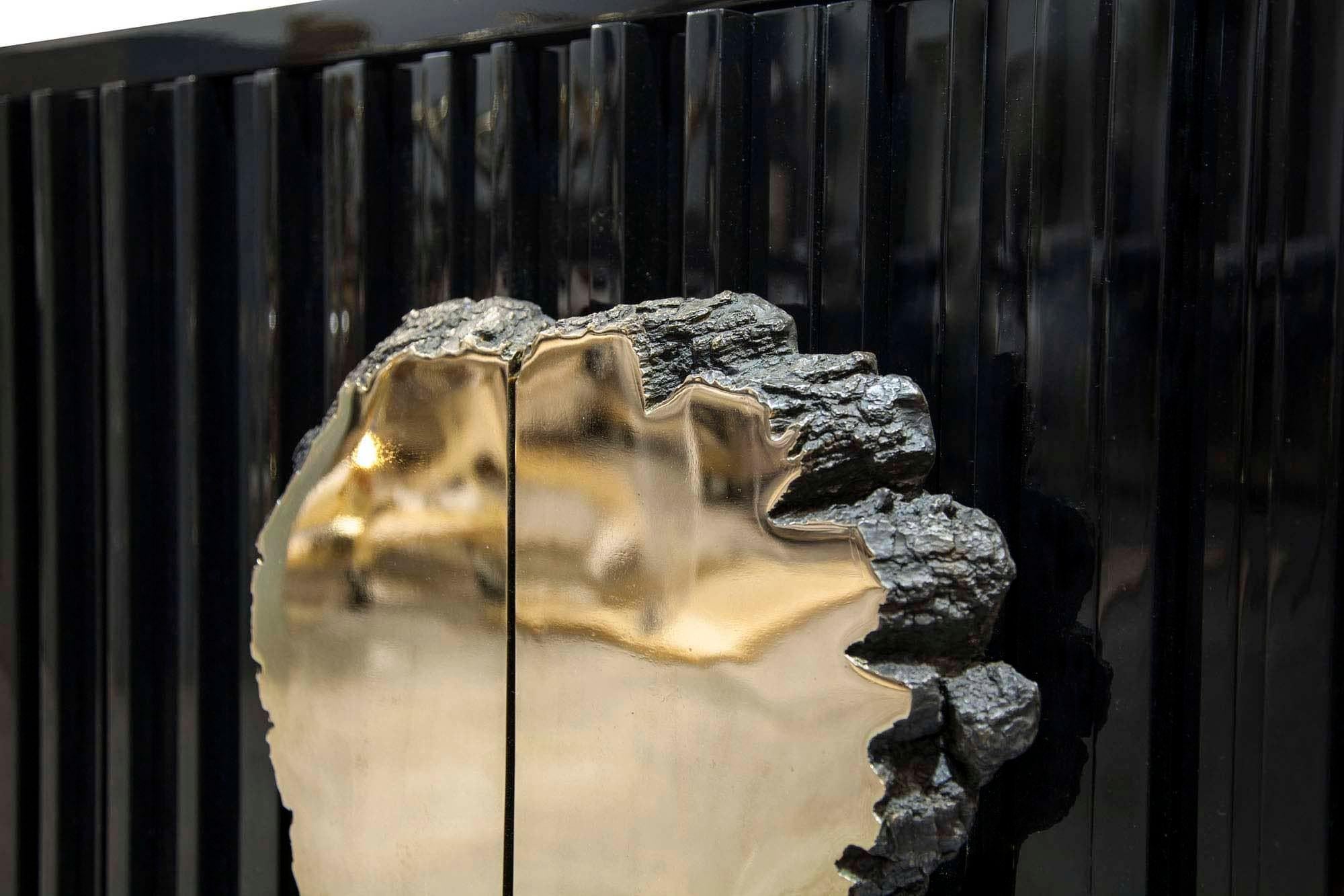 Un oggetto d'arte funzionale, la Credenza nera adotta strati meticolosi di sfaccettature di lacca nera di dimensioni variabili, sormontati da una spilla in bronzo lucido. Una celebrazione di stili gotici e moderni